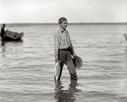 Washington, D.C., circa 1920. "Shad fishing on the Potomac." National Photo Company Collection glass negative. View full size.
Child Labor!Lewis Hine, where are you when we need you?
If you like bones ...... you'll love shad.  As far as I'm concerned it's so bony as to be scarcely edible.  Shad roe, in contrast, is one of life's finer delicacies.
Shoulda seen it !The one that got away was trying to eat this little guy.
No QuestionPlank it!
Deja VuOn the right is the bow of the boat seen in a previous post.
Fresh Water PigeonsShad are trashy fish and I don't understand why our ancestors once thought them so yummy.  Read Civil War history and you'll find numbers of references to "shad fries" or "shad bakes" given by soldiers.  Along reservoir shorelines in Ohio I've seen shad lying dead by the thousands, stiff as a board and rotting, blown onto land during a storm. Perhaps this young man in the corduroys never tasted a walleye.  
Plentiful and cheap = popular during hard timesMy guess would be that our ancestors found them so yummy simply because they were cheap and plentiful.  During the Civil War when those who should have been farming and fishing were instead fighting, food was scarce and expensive, so easily caught fish like shad were bound to be featured on the menu.
Get them debonedand they are delicious!  Shad have returned to the Delaware and the Hudson recently -- they are a yummy sign that spring is on the way!  
(The Gallery, D.C., Kids, Natl Photo, Sports)