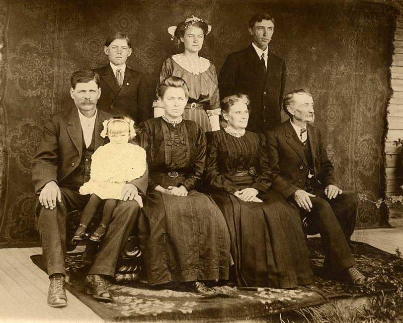This photo was taken in 1911 on the porch of the house built by the older mustached man sitting on the right, James A. Lovell Smith.  The family had recently migrated from near Boise, Idaho to Gueydan, Louisiana.  He and his son, F.T., (directly behind him) built and farmed the land in this rich rice-producing area.  The family still resides on the land today (2012), and the road in front of the house is named for F.T.'s son, F.T. Smith Jr. View full size.
