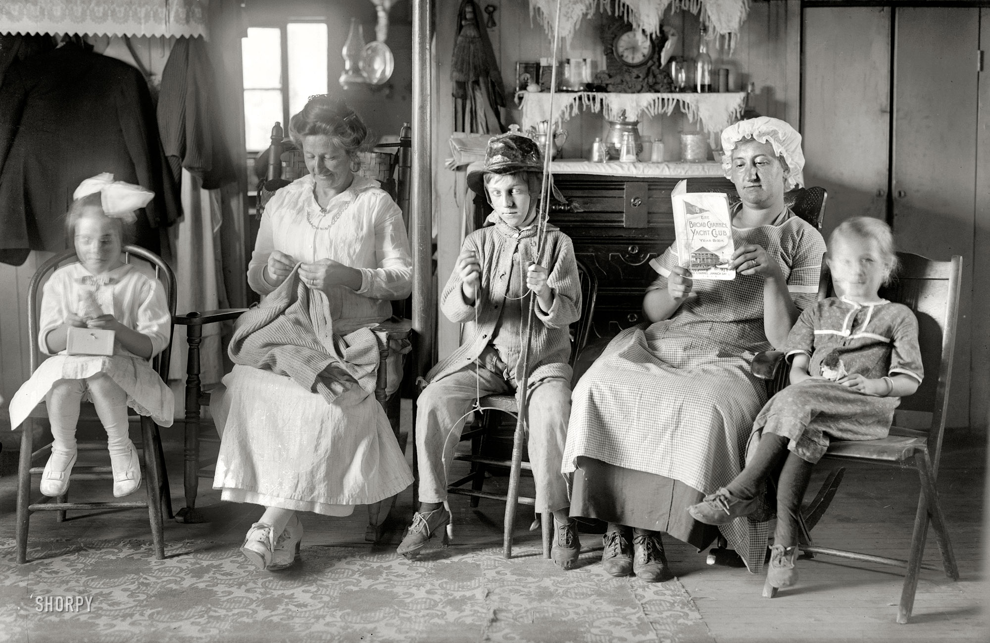 Queens County, New York, circa 1915. "At Broad Channel, in the living room." A cottage in the Jamaica Bay island colony, where the fish are biting and the sweaters need mending. 5x7 glass negative, Bain New Service. View full size.