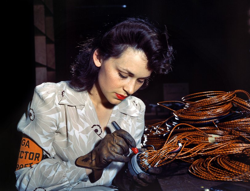 June 1942. Lockheed Vega aircraft plant at Burbank, California. "Hollywood missed a good bet when they overlooked this attractive aircraft worker, who is shown checking electrical sub-assemblies." View full size. 4x5 Kodachrome transparency by David Bransby for the Office of War Information.
