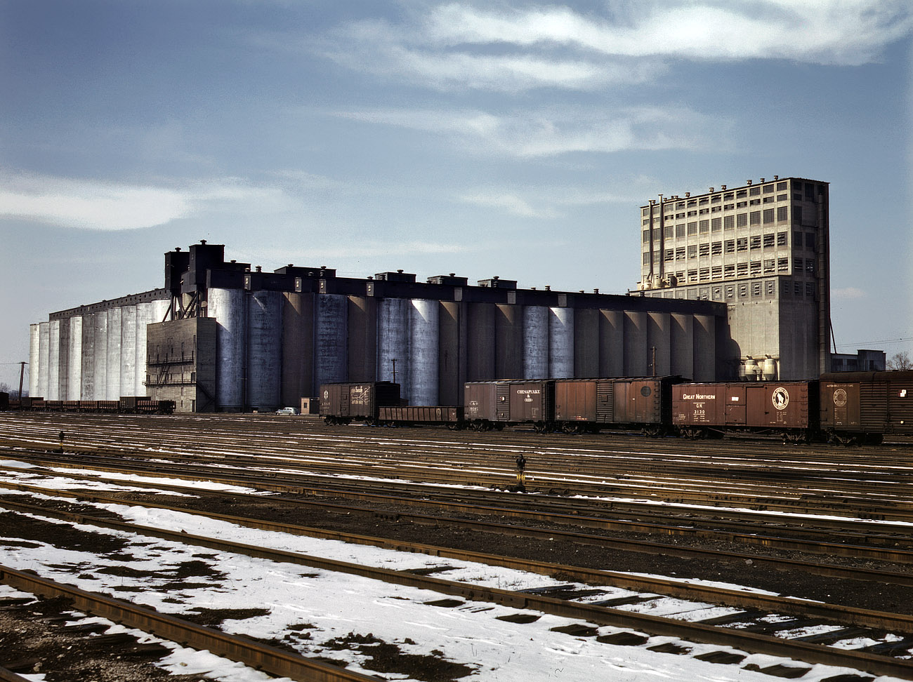 March 1943. The giant Santa Fe Elevator near Kansas City, demolished in the 1990s, held 10 million bushels of grain. View full size. 4x5 Kodachrome transparency by Jack Delano, Farm Security Administration/OWI.