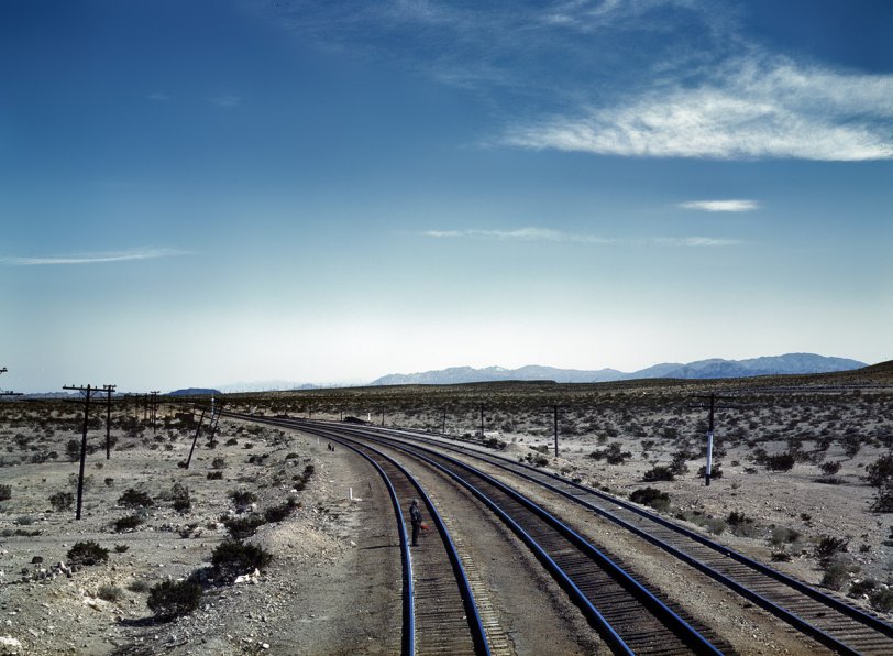 Flagman behind a Santa Fe R.R. westbound freight during a stop at Bagdad, Calif. March 1943. View full size. 4x5 Kodachrome transparency by Jack Delano.