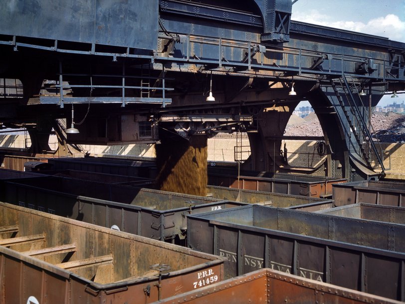 May 1943. Pennsylvania R.R. iron ore docks, Cleveland. "After the ore is weighed in the Hulett unloader it is dropped in the waiting hopper cars below." 4x5 Kodachrome transparency by Jack Delano for the OWI. View full size.
