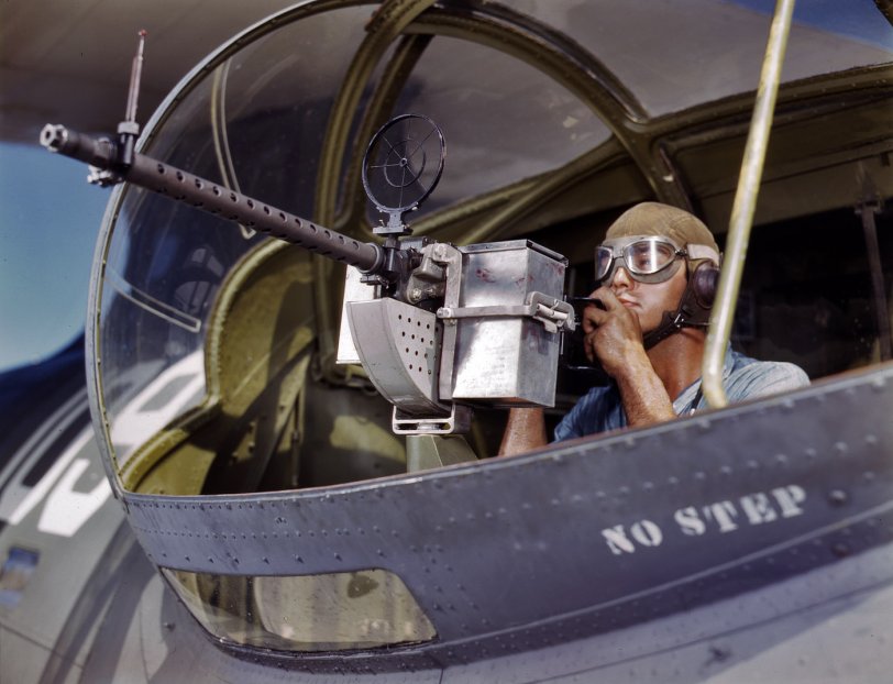 August 1942. Naval Air Base at Corpus Christi, Texas. Jesse Rhodes Waller, aviation ordnance mate third class, tries out a 30-caliber machine gun he has just installed in a Navy plane. View full size. 4x5 Kodachrome transparency by Howard Hollem for the Office of War Information.
