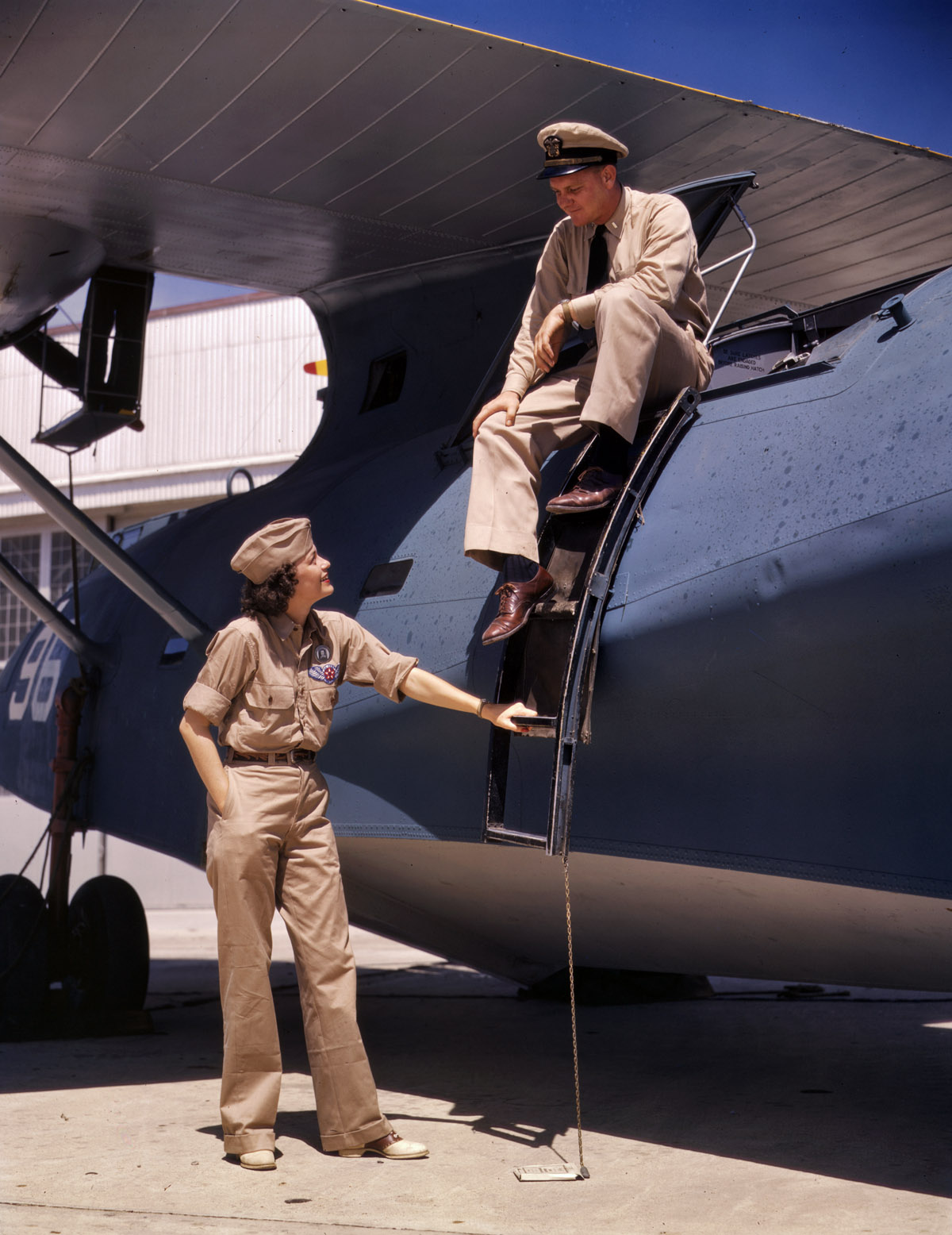 August 1942. Corpus Christi, Texas. "Mrs. Eloise J. Ellis, senior supervisor in the Assembly and Repairs Department of the Naval Air Base, talking with one of the men." 4x5 Kodachrome transparency by Howard Hollem. View full size.