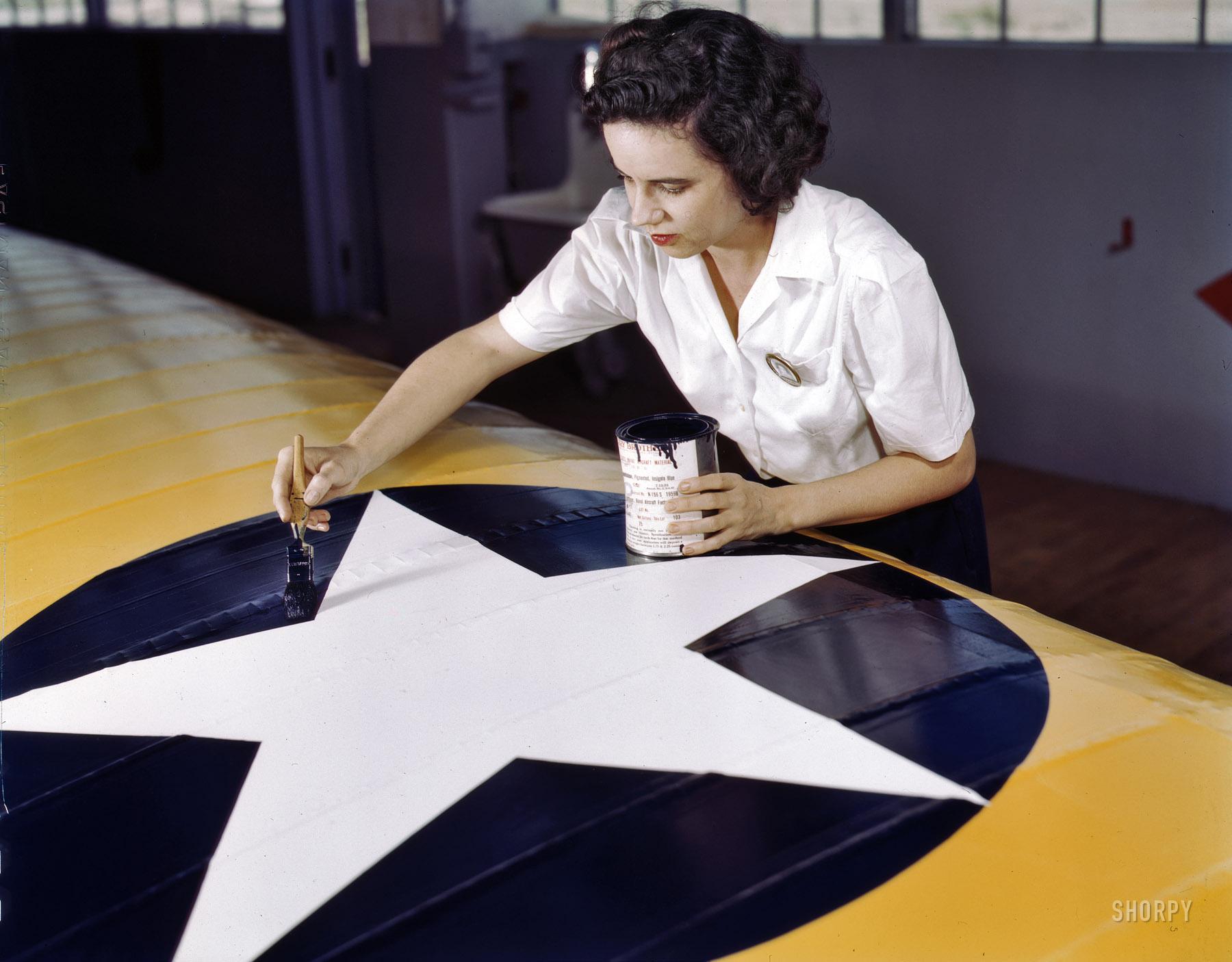 August 1942. Corpus Christi, Texas. "Women from all fields have joined the production army. Miss Grace Weaver, a civil service worker at the Naval Air Base and a schoolteacher before the war, is doing her part for victory along with her brother, who is a flying instructor in the Army. Miss Weaver paints the American insignia on repaired Navy plane wings." 4x5 Kodachrome transparency by Howard Hollem for the Office of War Information. View full size.