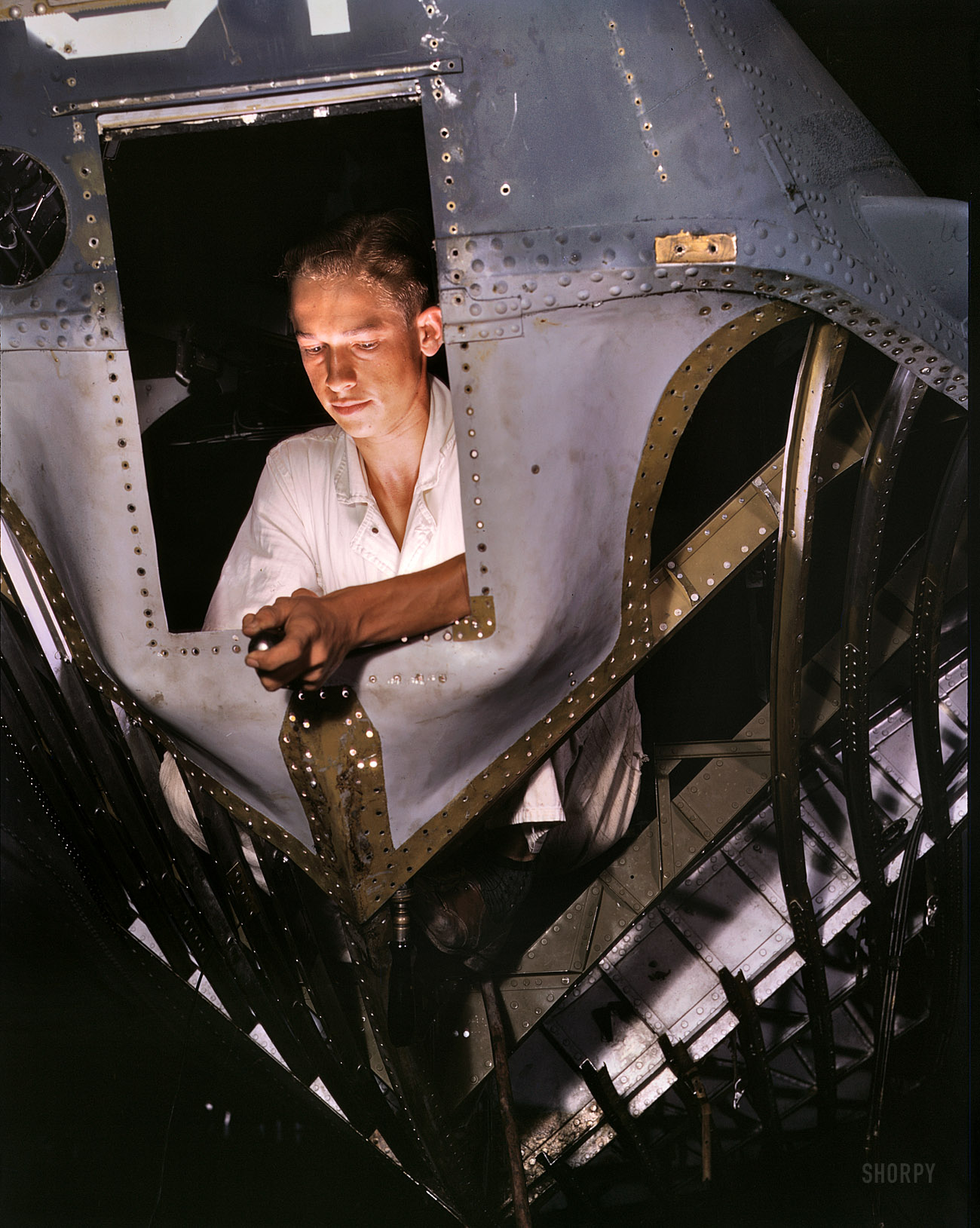 August 1942. "As an NYA trainee working inside the nose of a PBY, Elmer J. Pace is learning the construction of Navy planes at Corpus Christi Naval Air Base, Texas." 4x5 Kodachrome transparency by Howard Hollem. View full size.