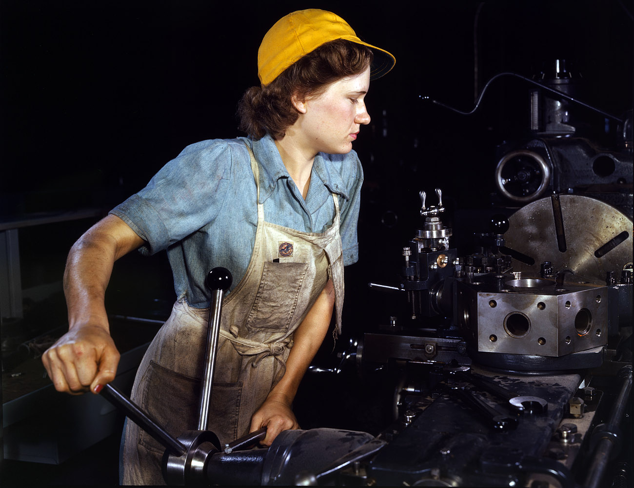 October 1942. Lathe operator machining parts for transport planes at the Consolidated Aircraft plant in Fort Worth, Texas. View full size. 4x5 Kodachrome transparency by Howard Hollem, Office of War Information.