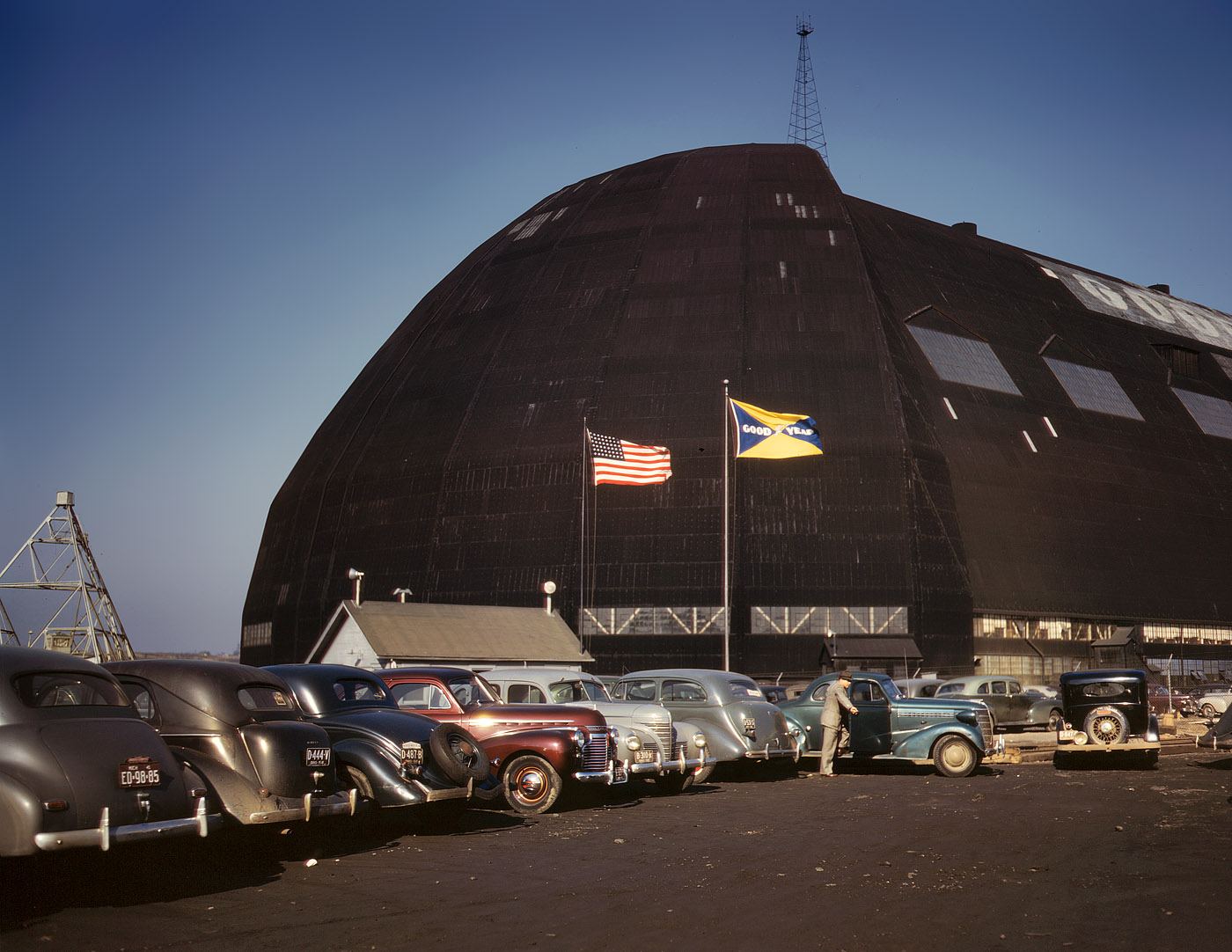 December 1941. Goodyear Aircraft, Akron, Ohio. "Formerly an aircraft dock, this huge building, thought to be the largest in the world with no interior supports, is now the scene of many busy shops turning out aircraft parts. Either new housing close to the plant or vastly improved public transportation will eventually have to be supplied, for the tires on the cars of the workers, and perhaps even the cars themselves, will in many instances give in before the end of the present emergency." View full size. 4x5 Kodachrome transparency by Alfred Palmer.