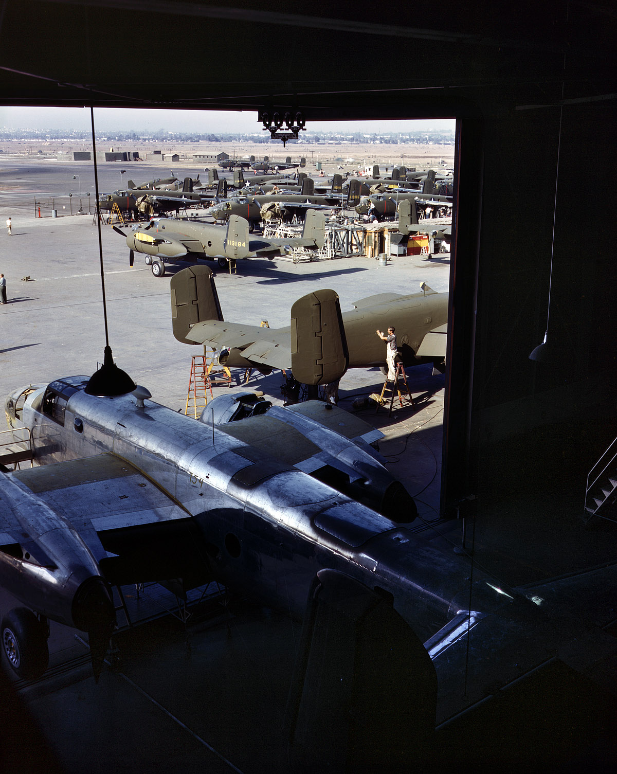 October 1942. "Another B-25 bomber rolls off the final assembly line to join other ships in the outdoor assembly area. North American Aviation Inc. Inglewood, California." View full size. 4x5 Kodachrome transparency by Alfred Palmer.