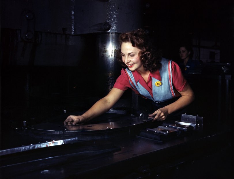 October 1942. Metal parts are placed on masonite by this employee before they slide under the multi-ton hydropress at North American Aviation in Inglewood, California. View full size. 4x5 Kodachrome transparency by Alfred Palmer.
