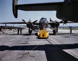 October 1942. "A new B-25 bomber is brought for a test hop to the flight line at the Kansas City, Kansas, plant of North American Aviation." 4x5 Kodachrome transparency by Alfred Palmer, Office of War Information. View full size.
Kansas, not California?The photo was more likely taken at the North American/Army aviation plant in Kansas City, KS (Fairfax) - not Long Beach as the caption says.  The white horizontal strip in the background is a graveled levee along the Missouri River.
The photo is probably taken near the old B-25 plant (NW of Fairfax Airport) with the plant to your left and looking north at the levee.
The Fairfax B-25 plant was demolished years ago and the Fairfax airport closed and re-developed into a GM auto plant.  Parts of this concrete apron are still there though.
Darby Steel was busy building most of the LCTs to be used in WW2 just to the west of the Fairfax B-25 plant.  KCK was a busy place in 1942.
[Original LOC caption for this photo: "A fast, hard-hitting new A-20 attack bomber is brought for a test hop to the flight line at the Long Beach, Calif., plant of Douglas Aircraft Company." Evidently someone got their planes (and factories) confused. - Dave]
For the record ...I did some more reading and the Darby facilities were apparently in the West Bottoms industrial district "south" of the Fairfax plant, where the Kaw River (Kansas River) joins the Missouri River, and not to the west of Fairfax.
One of the Fairfax B-25s returned to KC a couple of weeks ago for an airshow at the Downtown Airport, across the river from Fairfax.  One of the WASP ferry pilots showed up for a ride.
http://www.kansascity.com/news/local/story/1398087.html
Aircraft TugWith all due respect to the B-25s, the real hero of this image is the innocuous little yellow aircraft tug. To this day, tugs like this are a fixture on civilian and military airfields, as well as on aircraft carriers.  Its basic design has hardly changed for over 70 years and counting. 
Ahh, KodachromeI'm always so jealous when I see you've posted something from Kodachrome. That transparency probably looks as good as the day it was processed. What I'd give to be able to get some of the stuff for my 4x5. I'll just have to use up the two rolls of 25 speed I have before the end of next year.
(The Gallery, Kodachromes, Alfred Palmer, Aviation, WW2)