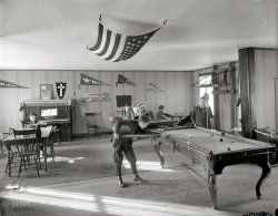 Circa 1912. "Neighborhood House, pool room." Another look at this Washington, D.C., settlement house. Harris &amp; Ewing Collection glass negative. View full size.
Playgrounds, Gymnasiums &amp; Baths

Washington Post, Oct 24, 1906 


Help Neighborhood House
Social Settlement in Southwest Applies for Incorporation

Charles F. Weller, General Secretary of the Associated Charities, his wife,  Mrs. Eugenia Winston Weller, and John B. Sieman, jr., yesterday filed with the recorder of deeds articles of incorporation of Neighborhood House the object of which is to carry on active social settlement work.  The corporation is to be perpetual, and its scope will include the conduct of social clubs and classes, educational and industrial work, and the maintenance of playgrounds, gymnasiums and baths.
It is proposed to hold summer outings, and to investigate industrial conditions and social problems and promote individual, neighborhood, and municipal improvement.
The institution and maintenance of philanthropic enterprises and the development of volunteer personal service in such work is to be part of the plan of the corporation.  Fourteen trustees are to manage the affairs of the institution for the first year.
Neighborhood house is located at 456 N street southwest, where it has been for the past five years.  Articles of incorporation were filed several months ago, but, on account of some technical defect in the papers, it was decided to reincorporate. Mr. Sieman said last night neighborhood house has been incorporated because the enterprise may some time be left property, and it is desired to have a legally constituted body to take title.

The Music ManWhere Is Harold Hill When You Need Him?
Trouble in River CityThis all looks so nice and progressive.  But I seem to recall pool was once a decadent activity a la Meredith Willson.
45 + 13Using my superpower for spotting trivia, the flag suspended from the ceiling is one that was in use from 1896 to 1908, after Utah was admitted to the union.     There were four more changes to the flag between 1908 and 1960 as five more US territories were recognised as states.
Any more and you're going to need a bigger flag.
[That's a 48-star flag in our photo. - Dave]
MagazineCan anyone tell what magazine the boy on the couch is reading?
QuestionThere's a cross on a shield hanging above the piano. Does anyone know what the letter "k" signifies?
Special KWhat's the K on the plaque above the piano represent?
48-star flag?No, that's not a 48-star flag.  A 48-star flag has six rows of eight stars.  This flag has staggered rows, not aligned rows.  (A 50-star flag also has staggered rows).
Hilcat
[Count the stars. Six rows of 8 makes 48. - Dave]
Prior to 1916 there was no official flag design. From the flag website nava.org:
Q: I have two different 48 state flags. One has 48 staggered stars and the other has eight equal rows across with six rows down.  Were there two different 48 state flags ever made? - Marla
A: Prior to 1916, there were no official specifications for US flags. Indeed these two variants show up right from the beginning of the 48 star flag in 1912.  After 1916, pretty much everyone switched to the even rows with the stars one over the other like the second one you mention.  48 star flags with staggered rows are somewhat rare and are early (1912-1916 or thereabouts).

Supersize me.What else do they suspend from those ceiling hooks?  The pool table?
Club Pennants The pennants on the wall represent the names of clubs at Neighborhood House.  The following article concerning the Spring Festival at the house talks of dances and skits put on by the clubs. Of special note is the "Pleasure Club Girls," a rather saucy name for a club of 14 to 16 year-olds.



Washington Post, Apr 27, 1913


Eleventh Spring Festival at Neighborhood House

...
The Golden Rule Club and the Merry Makers' Club, of girls a little older, give a masque of the children of fairyland and a May-pole dance by English shepherdesses.  In the evening the boys hold the stage, the True Americans and White Eagles giving a Robin Hood play, and the Progress and Young Builders clubs offering a minstrel show.
On Friday afternoon and Aztec and Bluemont clubs and several girls' clubs give the various May-day ceremonials of other countries.  in the evening is another play, given by the Pleasure Club Girls, of 14 to 16 years old.  This is "The Play of Merrymount," a May-day tale of gypsies and Puritans in 1626, written by Miss Constance McKay, and it is followed by scenes from "A Midsummer Night's Dream" by two young men's and young women's clubs, the Wyvern Girls Society and the Keystone Boys Club, the last feature of that day being Morris dances by the Olympia Boys' Club.
The last event of the festival is a version of "Hansel and Gretel," dramatized by Mrs. Eugenia Paul Jefferson, and acted by the Neighborhood Peace Club.

Mrs. Eugenia Paul JeffersonMrs. Jefferson was the daughter-in-law of the great American comedian Joseph Jefferson (1829-1905), famous for his portrayals of Rip Van Winkle. She was also the author of "Intimate Recollections of Joseph Jefferson," published by Dodd, Mead in 1909.
Pool RoomI shot many a game of pool in this place back in the late 30's and 40's.  The pool room was located upstairs over the gym in the alley back of the Neighborhood House. You entered through the gym, straight through to the back, and up the stairs.  Things changed a little from 1912 to the 30's and 40's because I don't ever remember seeing anyone wearing nice suits like those kids are.  Anyway, great memories.  Thanks.
(The Gallery, D.C., Harris + Ewing, Kids, Sports)