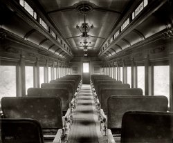 "Car interior. Washington &amp; Old Dominion R.R." Our third and final look at Pennsy car 4928 on the tracks of the W. &amp; O.D., whose right-of-way is now plied by commuters taking I-66 into Washington. 8x10 glass negative. View full size.
Next stop, Willoughby!It looks like the old railroad car in that "Twilight Zone" episode.
Is ComfyIt IS more comfy than a modern jetliner. I volunteer at a railroad museum where we refurbish and display old RR cars and have sat in many of these. The seats are like your couch at home; there is more than ample room to cross your legs and the passenger next to you can still get up and leave his seat without tripping over your legs. Some of the newer (1920s-30s) ones have pivoting seats that let the whole bench swivel toward the aisle.
Like so many modern things, the "good" has been engineered out of it. We used to get things such as durability and ruggedness for free, but now it's all designed out as unnecessary, as exemplified by the sardine-can seating of modern airliners.
[I'll bet airplane seats are pretty durable. And of course there's a reason airline seats are closer together. The per-mile cost of moving a pound of passenger through the air is much higher than it is on the ground. - Dave]
ContrastWhile a bit seedy and mussed up, the interior of Old 4928 looks fairly decent.   Like an old dowager queen waiting for a rescuer, hoping for salvation. But, alas, it probably never came and we are the worse off for that.
The W&amp;OD lives, sortaThe Washington &amp; Old Dominion ran from Alexandria out to Purcellville in the Blue Ridge Mountains. Today, its right-of-way is a much-used bike path that stretches from the west end of Alexandria west, passing through wooded areas, suburban sprawl, and eventually rural stretches as it gets outside the Washington Beltway. It's a wonderful trail to ride.
Most folks don't realize that one small (maybe a mile or two) of the RR still is in daily use: the stub that goes from the former Potomac Yard (and Conrail/Amtrak mainline) east into Old Town Alexandria, dead-ending as siding at the warehouses on the banks of the river. On a daily basis, two- and even three-engine trains of boxcars and coal hoppers pass by my office window, servicing the coal-fired Mirant power plant and the riverfront warehouses. With Old Town becoming increasingly an upscale tourist destination, it's nice to have reminders that it's still a working port!
W&amp;ODI-66 does not follow the W&amp;OD Railroad. The W&amp;OD's right of way is instead now a trail, from Shirlington to Purcellville. The right-of-way west of Purcellville was sold before the rest of it, so it will likely never extend further west than that.
[I-66 uses two stretches of W&amp;OD right-of-way through Arlington. - Dave]
Looks ComfyThis car looks about 1000 times more comfortable than the coach seats in a modern jetliner (and the TGV trains in Europe for that matter).
Doesn&#039;t look comfortableHard wooden armrests, scratchy fabric, no headrests, and no lumbar support all add up to uncomfortable in my book.
All Aboard...When I was a child, and the Pennsylvania Railroad had not yet become Penn Central, there were still 1910-1938 era cars in use similar to this one.
Far from being uncomfortable, they had soft mohair seats with very plush and pliable springs, and those seatbacks could be shifted to the front or back of each bench, allowing one to ride facing forward, back, or to create two adjacent seats that faced each other for a cozy group alcove. None I ever rode on had carpet runners like this one. They had linoleum or tile.
The thing you cannot see in the picture is how noisy those very oldest cars were to ride in. The windows, when they were wood, banged, and the tracks were not yet welded into a seamless beam (done for the Metroliner in the 1970's), so at every segment of rail the windows rattled and the train went clack-clack-clack. 
The silversides of today are quiet and smooth riding, but they have none of the art deco and pre-WWI charm of these cars. Each train ride was an excursion into art history. You never knew in advance what art era you would be studying.
W&amp;OD TrailHere's a map showing the trail.
(The Gallery, D.C., Harris + Ewing, Railroads)