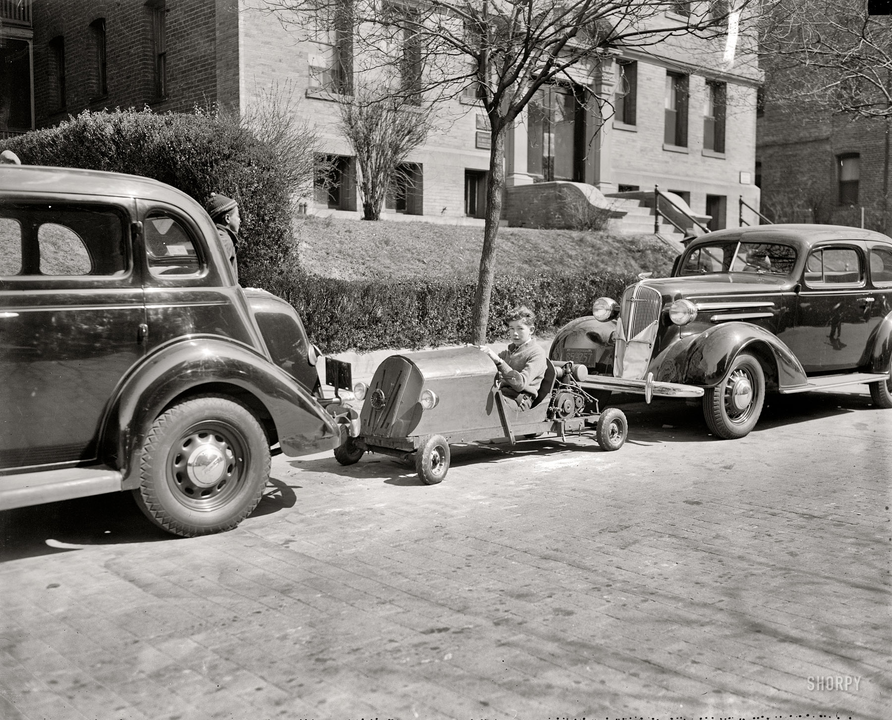 March 30, 1937. "Transportation and no parking worries. Nelm Clark, 16-year old Washington, D.C., youngster, solved this problem by combining a lawn mower motor with a set of motorcycle gears to make this unusual midget auto. Costing $60 to build, the contraption weighs only 150 pounds -- the weight is its main feature -- and if you run out of gas you easily push it or tuck it under your arm and walk home." Harris & Ewing Collection glass negative. View full size.