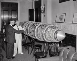June 9, 1937. "Congress sees model of new proposed American-designed dirigible. Rep. Edward A. Kenney (right) of New Jersey, Chairman of the House Interstate Commerce Committee, viewing a model of a new American designed dirigible displayed at the Capitol today. Roland B. Respess, President of the Respess Aeronautical Engineering Corp., is pointing out the features of the ship to the House member. The House Interstate Subcommittee is hearing the witness on a bill recently introduced to authorize the loan of $12 million for constructing two eight-million-cubic-foot dirigible airships, a large American airship plane, and Atlantic operating terminal with a view toward establishing twice-a-week Trans-Atlantic airship service." Harris & Ewing glass negative. View full size.