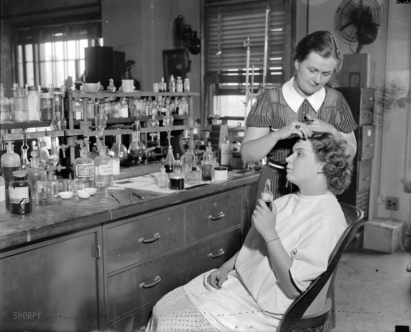 July 10, 1937. Washington, D.C. "Testing cosmetics for the government. Mrs. R. Goodman is shown sitting with Mrs. C.R. West applying dye for the hair. Some dyes contain lead and the poison in the dye may lead to chronic poisoning. The Department of Agriculture is continually on the lookout for false labels and advertising." Harris & Ewing Collection glass negative. View full size.