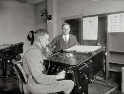 October 2, 1922. Washington, D.C. "Ford Target Computor. Capt. H.E. Ely." An electro-mechanical approach to the aiming of large artillery pieces. National Photo Company Collection glass negative. View full size.
Tech SupportAn analog trunk-line call to India was a spot of bother in 1922.
Hello? Tech Support?"I've been holding for fifteen minutes ... Oh, wait, they're coming on now. Hello? Hello? Can you speak up please? You sound like you're in India or something. Yes, OK ... I was going along fine and then everything just froze and I got a message about an 'illegal operation.' Right. And now nothing works. Uh huh. You say I should ... restart the computor and that should take care of it? That's it? Wait, hello? Hello?"
Model 1?As noted below, Hannibal C. Ford developed target computers for the U.S. Navy.
It's odd that Capt. Ely in the photo seems to be an Army officer rather than Navy, because the first applications for target computers were for navies.  The British developed the first one, the Dreyer Table and the Dumaresq, prior to World War I and used it during the war.  Mr. Ford was somehow exposed to the British technology -- I forget the details of this but it's covered in a series of articles in Warship International magazine.  But he also had his own original ideas, and the Ford computer was considerably smaller than the Dreyer Table and looked quite different.
Inherently, in the battleship era, guns on ships required calculated aiming because both the firing and the target ship could be moving in different directions at different speeds, and the guns could often outrange the horizon from the point of view of deck level.  A "gun director" on a tall tower could measure range and bearing with a powerful binocular range finder, and those measurements were transmitted to the computer mechanically or electrically.  The computer then calculated the bearing and elevation at which the guns should fire to score a hit.
In 1985, I attended the sea trials of the restored battleship Iowa.  I saw the Ford range computer.  It was a different model than the one in the photo, considerably larger, but it still had the clear cover (probably glass to begin with and Lexan when I saw it) seen in the photo.  Underneath you could see a maze of gears and linkages, color coded, for maintenance I guess.  It had its own room with electrical panels on the bulkheads.  In the Wikipedia article it explains that the device weighed over a ton, but of course on a batteship that doesn't matter.  There was no graph plotter as shown in the photo.
Still unresolved is why the Army was interested in this device at a period when its artillery was normally attacking stationary targets from a stationary position.  In 1922, could there have been research on antiaircraft fire direction?  Possibly.  Or maybe Mr. Ford was just covering all his possible customers.
Related question: is the civilian in the background Mr. Ford himself?
Hannibal FordThe Ford Instrument Company, Long Island City, NY, was formed by Hannibal Ford in 1915. It built analog fire control computers in the pre-electronic days. The company was later merged into the Sperry Corp.
Dad&#039;s serviceMy father's stint in the Army during WWII (Battle of the Bulge, crossing of the Rhine and Ruhr) had him working as a "Computer" for anti-aircraft artillery. He used some kind of calculating device for aiming the big guns, but I have no idea what kind. I can't ask him because he's in Arlington now.
Fire ControlA few months ago I toured the USS North Carolina battleship in Wilmington and saw the targeting command center. There are several large rooms completely full of enormous computers used to track enemy ships, planes, and also to properly guide missiles and guns. I'd say there were at least 30-40 of these massive vacuum-tube computers paired to walls of controls on either side. The level of complexity was amazing. 
Field ArtilleryWhen I was in the Army's Artillery School (mid 1970's) at Fort Sill, Oklahoma we had something called a FADAC (field artillery digital automatic computer) to aid in positioning artillery rounds on a target.  Was this an early version of FADAC?
The Forddid the same job -- providing aiming data for artillery -- but it was not digital like the FADAC.  It was an electromechanical analog device.  
There were precisely machined gears and shafts driving dials/pointers either mechanically or by controlling variable rheostats to drive indicating voltmeter dials.  Operators input data on the location of the target and the weapons, as well as factors like wind and temperature by setting voltages or turning shafts to certain angles.
The operators then read off the firing data and transmitted it to the appropriate Fire Direction Center personnel who passed it on to the firing batteries.  
Manual FDCI was likewise in Fire Direction Control, trained at Fort Sill.  Never saw a contraption like this while I was there, but we were taught how to find deflection and elevation for the artillery pieces using slide rules, while plotting targets on a grid board and finding range with a range/deflection protractor (RDP).  This was in the early 1990's.  Of course, once I left the training school I never used such manual devices again; nevertheless, every Marine Corps artillery FDC still packs the manual tools--RDP, chart board with plotting pins, slide rules and books--just in case the primary and backup computers fail. 
Where are the flippers?And how many points does it take to get a free game?  I can't even light up the "special" bumper yet!
Back to the Plotting BoardThe October 1923 issue of the Coast Artillery Journal has a report (starting on Page 349) on various mechanical fire-control devices including the Ford Target Computer and Ford Battery Computer, which were tested as replacements for manual plotting boards. Among the findings:
a. They are complicated and frequently get out of working order.
b. They require very expert operators who should be trained for several months.
c. A trained mechanic is required for even minor repairs.
d. They operate solely by electric power.
e. Too much time is required for changing target and base line, and these operations require special skill.
f. The azimuth dials are hard to read, resulting in frequent errors. ...
i. They are noisy, making telephone conversation difficult in their vicinity.
Tests indicate that the Ford Target Computer, operated by and under the supervision of the Ford Company's engineer, frequently failed and, when in working order, gave results little if any better, either in accuracy or time of operation, than might be expected from a properly designed manual plotting board at ranges which permit a scale of 300 yards to the inch, if the board be carefully adjusted and skillfully operated.
It's interesting to note that fire control (i.e. "solving the range triangle" for the aiming of large artillery guns, which involves lots of trigonometry and a spot or two of calculus) was among the very earliest applications for digital computers in the 1940s.
A Royal Inspection During World War 2 my mother was stationed on anti-aircraft batteries including one in Hyde Park, which was frequently visited by VIPs. This photo shows Queen Elizabeth (the "Queen Mum," in interesting boots!) inspecting the battery. To the right is a gunnery "predictor." It required two people to keep the target plane on cross-hairs in two sights on the top and lots of cogs, gears and electricity to do the sums of where to point the guns. It looks very like the M7 model described here.
Ordnance CorpsWith reference to Captain Jack's question, Capt. Ely is wearing Ordnance Corps insignia, not Artillery, so I assume this was just an early procurement test of some sort.
The Queen Mum&#039;s Boots - - -aren't boots at all, but galoshes.  They kept our feet and shoes dry in wet weather.  Oh oh, now I've given away how old I am.  Yech.
Ely of CantignyUpdate: Upon further inspection of the photo and considering the caption of "Capt.", it may be that the uniformed man in the photograph is Hanson Edward Ely, Jr., son of the "Ely of Cantigny." Both son and father (Major General Hanson Edward Ely, Sr.) are buried at Arlington Cemetery.



Washington Post, Apr 30 1958 


Gen. H.E. Ely Is Dead at 90
By Dorrie Davenport (Staff Reporter)
Maj. Gen. Hanson Edward Ely, USA (ret.), known as "Ely of Cantigny" for his leadership of the 28th infantry which captured Cantigny on May 28, 1918 died Monday in Atlantic Beach, Fla.  He was 90.
He was one of the first officers sent abroad to study the Allies' trench fighting tactics and was later made chief of staff of the First Division
Repeated requests for troop duty gave him command of the 28th Infantry and his leadership in the Battle of Cantigny convinced European doubters of the fighting qualities of American soldiers.
Raised to brigadier general, he was head of the Second Brigade of the Second Division when the Americans captured Vierzey, near Soissons, in July 18, 1918.
In order to direct the attack personally, Gen. Ely attempted to enter Vierzey before it was cleared of the enemy.  Fired on at short range by machine guns, he attacked and enabled his men to take the town despite strong resistance by vastly superior numbers.
Gen. Ely was cited for "indomitable bravery, disregard for his own safety and devotion to his men."  During the battle of Vierzey, his troops took more than 7000 prisoners.
It was "Ely of Cantigny" who, in command of the Fifth Division and promoted to major general, achieved what has been hailed as one of the outstanding major exploits of the Army Expeditionary Force when it forced its way across the Meuse at Dun-sur-Meuse.
Gen. John J. Pershing wrote that "this operation was one of the most brilliant feats in the history of the American Army in France."
Years before his World War I exploits, he had been given a silver star for "gallantry in action against insurgent forces at Taliahan River, Luzon, Phillippine Islands, March 25, 1899."
When soon afterwards Gen. Frederick Funston formed his celebrated mounted scout unit, Hanson Ely was listed as its commander.
His 44 years in the Army included serving as a lieutenant in the Spanish American War.  Considered one of the most forceful figures in military service, he was considered as a leading authority on modern tactic and battle leadership.
After World War I, he reverted to his permanent grade of colonel but Congress, in 1921, endorsed his appointment as brigadier general and his promotion in 1932 to major general.
...

Army coastal artilleryIt's odd that Capt. Ely in the photo seems to be an Army officer rather than Navy
Coastal artillery was an Army responsibility. For example, Army Fort MacArthur (named for Douglas MacArthur's father) protected Los Angeles harbor. The big concrete emplacements are still there, for guns up to 16". In the 50s the guns were replaced with Nike nuclear missiles.
The Fort MacArthur Museum web site has more fun facts.
The 14" batteries look like baseball diamonds from above.
View Larger Map
(Technology, The Gallery, D.C., Natl Photo)