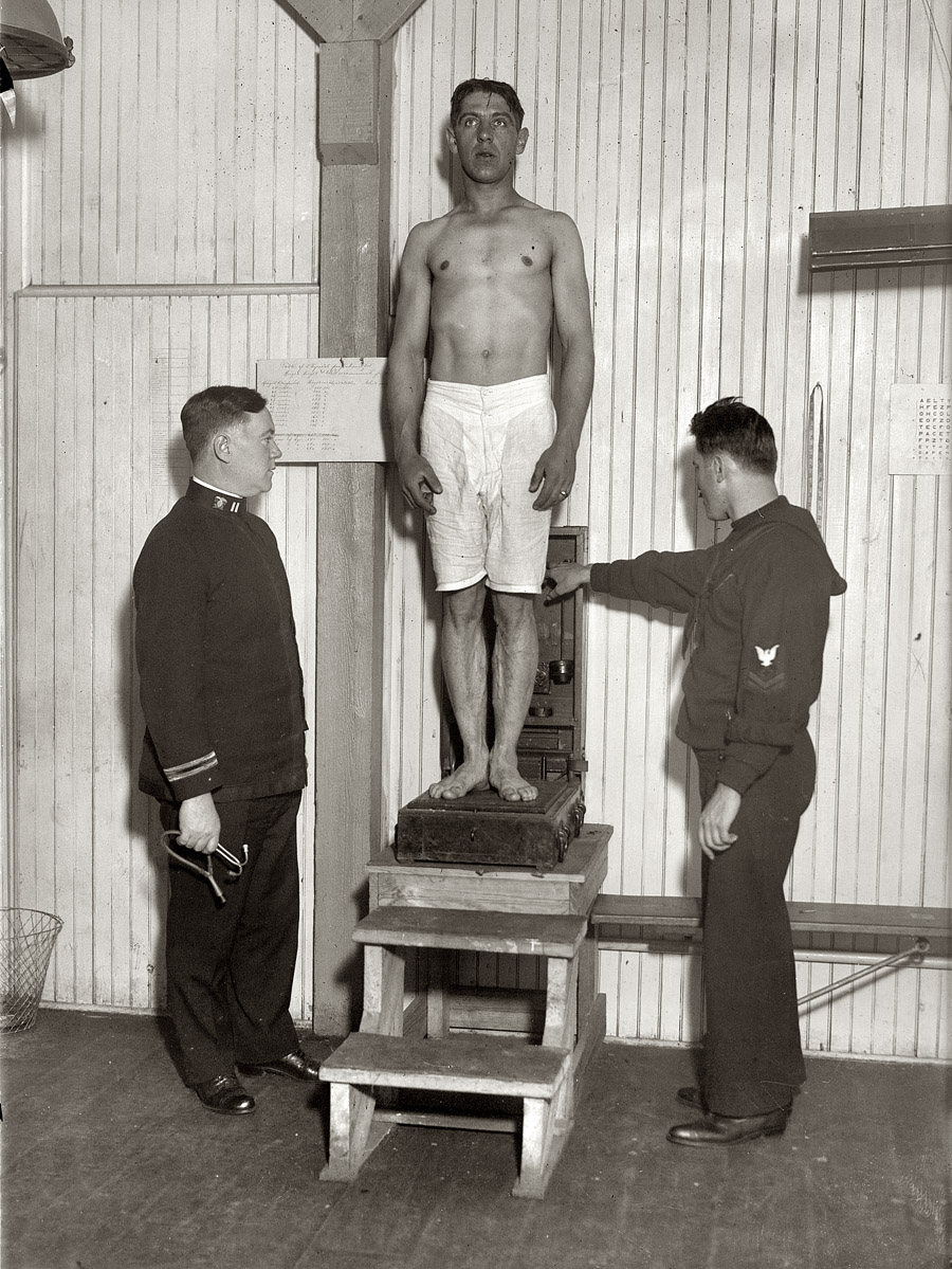 New York, 1917. "Examination on Recruit." Our inductee gets weighed aboard the "landship" in Union Square. View full size. Geo. Grantham Bain Collection.