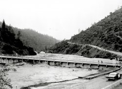 Record rainfall in the Sierra Nevada mountains in December 1964 caused water to breach the yet uncompleted Hell Hole Reservoir Dam located 40 miles east of the City of Auburn, Placer County, California. As the water surge arrived at the Highway 49 Bridge between Auburn and Cool, the Highway 49 bridge was completely destroyed, while the older concrete railroad crossing in the background survives to this day. Norm Sayler Collection, Donner Summit Historical Society. View full size.
(ShorpyBlog, Member Gallery)