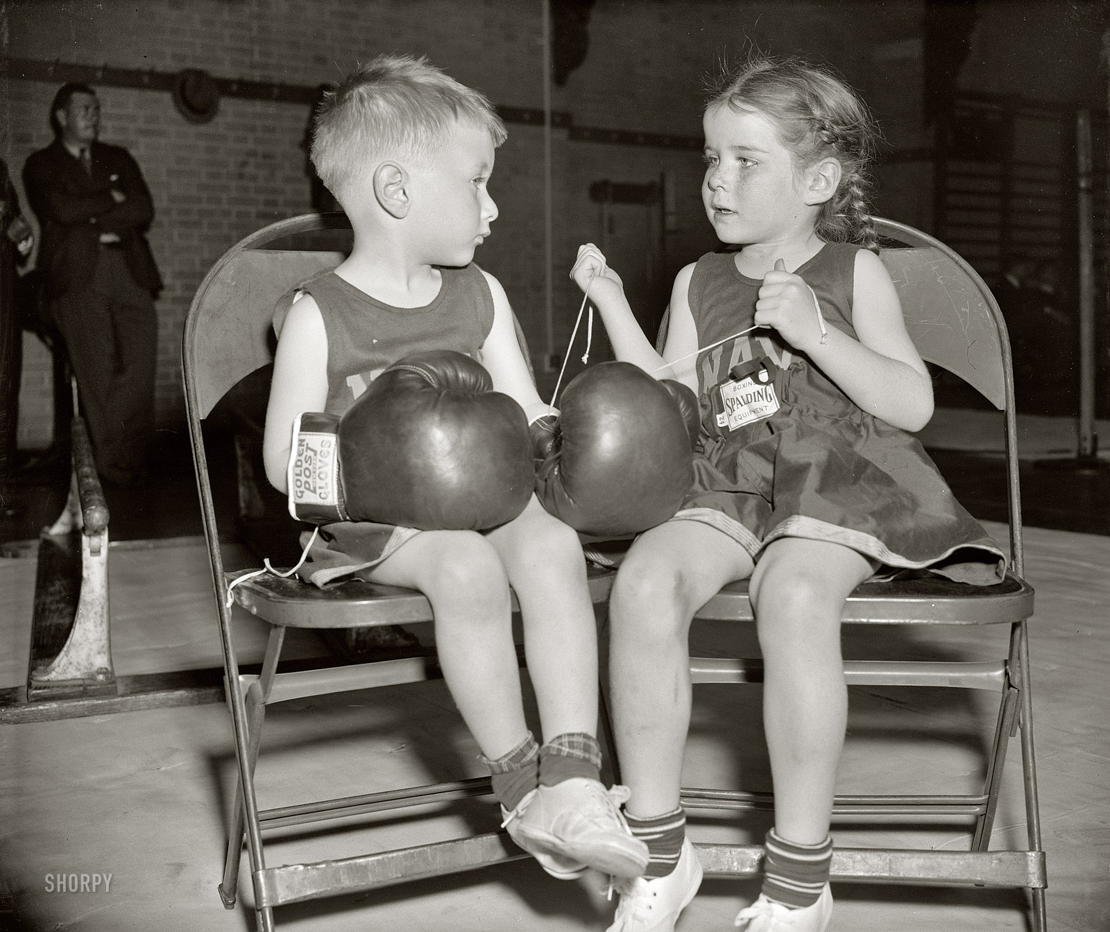 April 15, 1939. Annapolis, Maryland. "Dorothy Wood, 5, saw to it that her small friend, 'Chuck' Andrews, 3, wasn't being framed by some of the boys who hang around these places. She laced on his gloves herself. The occasion was the Naval Academy's 20th Annual Junior Boxing Championships." View full size.