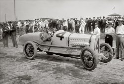 June 1, 1918. The Italian racecar driver Ralph DePalma and mechanic in the Packard that won the Harkness Handicap at Sheepshead Bay Speedway in Brooklyn. 5x7 glass negative, George Grantham Bain Collection. View full size.
Life imitating toyLiving in an age of more robust machines and concern for safety, it is hard not to look at this racing car and imagine that you are looking at a child's toy made life-size. Were sportsmen more innocent or more courageous to go nearly 100 mph in such a fragile-looking contraption? Who would do it today?
[Some of these cars went a lot faster than 100 mph. The average speed for the top finishers in this race was 103. - Dave]
Probably not really a Hemingway quote....but this shot reminded me of it. 
"There are only three sports: bullfighting, motor racing, and mountaineering; all the rest are merely games.”
Dashing fellowsThey had a different attitude toward risk in those days, letting it all hang out in an open roadster on natural-rubber tires and sitting in front of a large gas tank at speeds approaching 100 mph.
These large-format glass negatives continue to impress me, you can pick out impressive amounts of detail, everything from the spilled top-off oil on the frame, to the retaining screws for the clincher rims, to those fascinating ventilated drum brakes, is crystal clear.
Thanks Dave, now I'll be daydreaming all morning!
One of the legendsDePalma is one of the great legends of Indianapolis, right up there with Mario Andretti and A.J. Foyt.
Land Speed RecordDePalma was born in Italy and immigrated to the U.S. before the turn of the century. In 1912 and 1914 he was recognized as the AAA National Champion and in 1929 as the Canadian Champion. As late as 1936 he was still setting records in stock cars. His career victory total of 24 championship race wins still ranks high on the all-time list and came in a combination of road and course, dirt track, board track and oval track competition. He also competed successfully in Europe and helped design the Packard V-12, which he drove to a land speed record of 149.87 mph at Daytona Beach in 1919.
(The Gallery, Cars, Trucks, Buses, G.G. Bain, NYC, Sports)