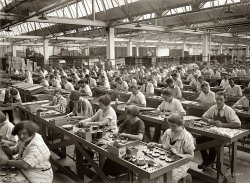 1925. "Condenser assembling department." Another view of workers putting radios together at the vast Atwater Kent factory in Philadelphia. View full size. National Photo Company Collection glass negative, Library of Congress.
Erector set buildersAll those little nuts and bolts and plates to put together! Now the radio-tuning task is done with a semiconductor diode. The new factories are full of billion-dollar machines and the workers just keep them fed. 
Could They Fill That Shop Today?I really wish the US had all that manufacturing going on today. I do wonder if we could fill those jobs though or whether the employers would have to look for illegal immigrants. Once thing is for sure, we're a soft and spoiled bunch compared to those folks.
Ship Shape ShopYou'd think this type of work would make people out of shape, but other than the lady in the foreground, not a single person in the picture can pinch an inch of fat. They are all perfectly slender. But then again, none of these people had Big Macs for lunch and dinner at Appleby's.
Economics 101"I really wish the US had all that manufacturing going on today"
You're right--imagine how our economy would look if when you walked into a Best Buy or Circuit City all those products were made in this country--all the wealth being kept here.
[If all those products were made here, there wouldn't be a Best Buy or Circuit City. - Dave]
(Technology, The Gallery, Factories, Natl Photo, Philadelphia)
