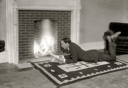 New York circa 1919. The producer, playwright and director  Stuart Walker, who had a long career in theater and film, spending a quiet night at home tossing scripts into the fire. George Grantham Bain Collection glass negative. View full size.
Odd Choice of Rug for a New York PlaywrightAm I really the first one to comment on the swastikas on this rug? 
They are backwards swastikas (I think). They predate the Nazi era by at least 15-20 years. 
I think I heard something about the swastika being an American Indian symbol for peace or something.
Decorating Faux PasGuess that rug wouldn't be a popular home decor accessory in a few years from when this picture was taken, all thanks to a certain bunch of Germans... It's amazing how many people think the swastika originated with the Nazis.
How cozy.Interesting motif on the fireside rug.
Interesting Indian RugVery interesting geometric designs on that rug, especially at the corners. Otherwise, it seems like a pleasant homey scene.
Fireside rug motif..very interesting!
Interesting rugLooks like an Indian rug from the Southwest. Those aren't swastikas, they're the four corners of the universe, I think. Or the Navajo called it the "whirling winds".
What&#039;s withWhat's with the swastika rug design Adolf??  
Carpet For SaleTwenty years or so later, the Indian patterns on his rug would mean something so very different!
Nice swastikasProducer, playwright, director... and Nazi? Or is this a case of the older, perhaps Hindu, use of the symbol?
Lucky rugNotice the swastikas on the rug, which were considered good luck symbols and certainly ubiquitous before its subsequent notoriety.
Are they Swastikas?When one gets as old as I am, one's brain file is so crammed full of facts that we tend to be unable to remember things we learned.   I do know that I did learn about the origin of the swastika, but in 1919 it was not yet a Nazi symbol.  It might have been an early American Indian symbol but it had a different meaning than it does now.  Also, that is not a very safe fireplace, it is an accident waiting to happen.  Maybe he was destroying manuscripts he disliked since shredders were not yet invented.
I love the swastikaI love the swastika rug.....must be from Asia, and is a symbol of good fortune since Nazis came later. 
&quot;Good Luck&quot; SwastikasStuart Walker's hearth rug is a nice tourist-quality Navajo wool rug of the sort that could be purchased in Santa Fe train station gift shops throughout the Southwest, as well as in East Coast department stores. From about 1895 to about 1930, Native American swastikas were a popular mainstream American "Good Luck" symbol, and were often paired with horseshoe and even shamrock motifs as good luck charms. Americans were also familiar with the many Chinese "Good Luck" swastikas seen on imported carpets, wood carvings and vases. 
During this period the silversmiths Daniel Low &amp; Co., of Salem, Mass., manufactured thousands of small sterling silver swastika charms for bracelets, earrings, pins and watch fobs, which sold quite well in Low's mail-order catalogs. Almost all American "Good Luck" swastikas disappeared with the start of World War II, and the terrible meaning of the Nazi swastika has erased these harmless "Good Luck" swastikas from our collective memory.
Now I knowNow I know why I never was published. What can I say?
RuggedIt's almost certainly a Native American, probably Navajo, rug. I'm pretty sure the design in the center part is still used on them. And yes, if it was still around 20 years later that rug probably went in the fire, too.
Unfortunate designThe first thing I noticed were the swastikas on the rug, but then I noticed the date in the caption. Strange how history can change the way we view things that were once commonplace. 
Interesting Swastikas....There are Swastika's in each corner of the carpet and the main emblem looks like a derivative. I wonder if it is an East Indian rug.
They Runed ItIt's very sad, the way the Nazis usurped the swastika.  The Nazis were very much into paganism, and used many pagan runes for their symbols as well.
Floor covering designThe kitchen floor covering in my grandmother's old home was factory printed with swastika symbols. I think it was installed in the 1920's.
Navajo RugThe one poster was exactly right that this is a Navajo rug woven by hand using wool from sheep raised by the family and probably mostly natural dyes.  It would be worth a couple thousand dollars in today's market, swastikas notwithstanding.
A little about the swastikaThe swastika exists in more cultures than just Native American or Hindu. Further, it's not so much that the Nazis were into paganism, but that they borrowed signs of power from a variety of cultures to symbolize and encourage their own power. The swastika and double lightning bolts, as examples, are symbologically memorable and strong, which is why they appealed to the Nazis. Further, the Nazis altered the symbols slightly to make them *more* powerful and unique to themselves, such as turning the swastika 45 degrees so that it appears to spin, and the arms are going clockwise. There's a fascinating chapter about who chose which symbols for the Nazi party, and why, in the book Dictionary of Symbols.
Use of The Swastikawas so very common in design and in marketing.  The Ladies Home Journal had a mail-in "Swastika Club" for young girls in 1910.  Members got a swastika badge and materials teaching good homemaking practices.  I think that the magazine had a monthly column aimed at members.
SpringtimeMax Bialystock searches for the perfect flop...
Pristine fireplaceThat's the most sparkling-clean fireplace I've ever seen. Any thoughts on whether this was a new home, a seldom-used fireplace, or whether Walker's housekeeper spent her days scrubbing bricks and mortar?
My mom has a large decorative garden urn which has been in her family since the 1920s and is decorated with swastikas. Needless to say, we've always felt it prudent to keep it in a spot where casual acquaintances don't see it.
[That might be asbestos board painted to look like bricks. - Dave]
NOT a swastika.The swastika is made from four backward 7s (an easy way to remember) but what you see in the pictures is, among other things, is a Native American symbol representing the thunderbird. NOTE:  made from forward 7s.
[Incorrect. Swastikas can go either way; the Native American symbol is also a swastika. - Dave]
(The Gallery, G.G. Bain, NYC)
