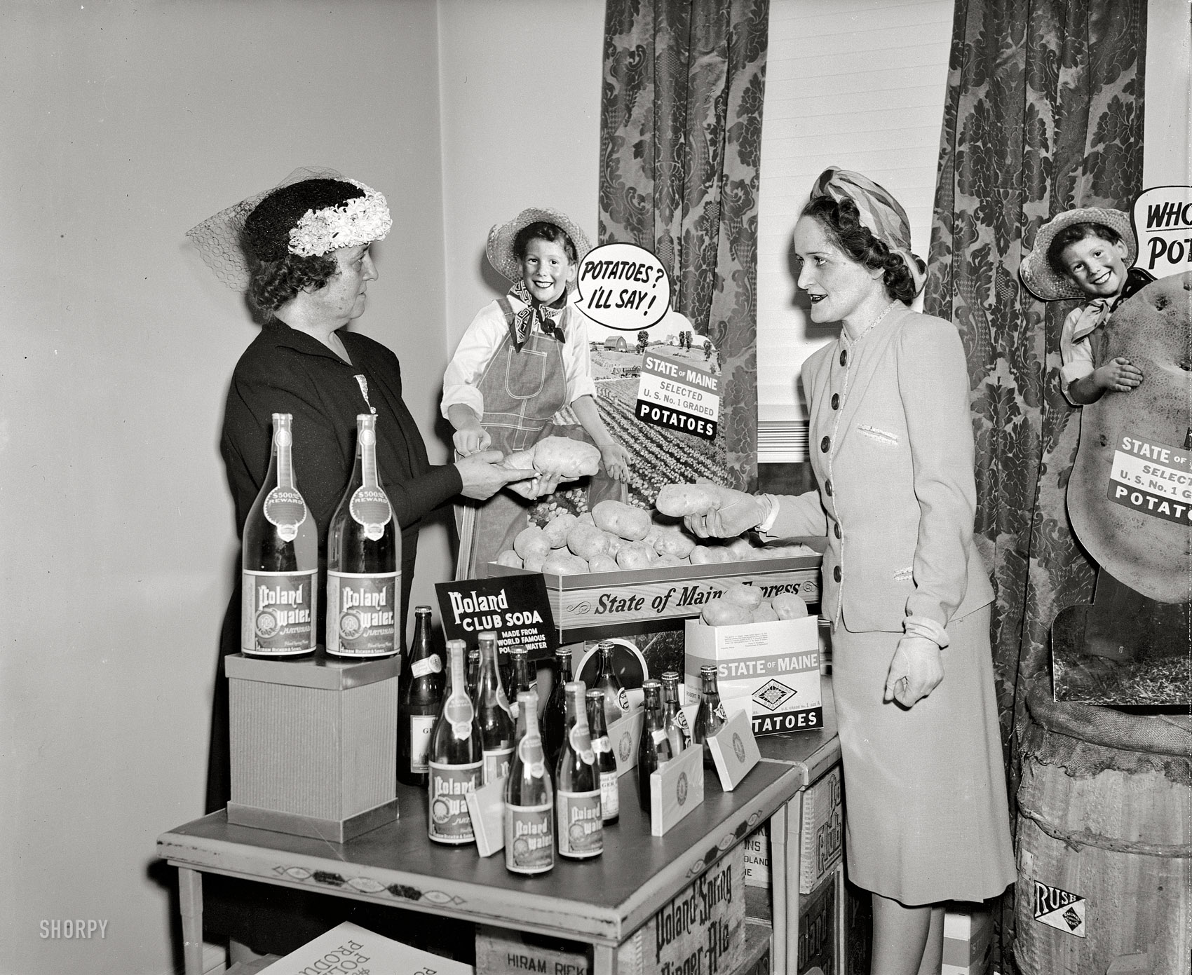 Washington, D.C., circa 1940. "Caption missing." A table laden with delicacies from Maine, attended by two ladies who seem to be debating the merits of their respective spuds. Harris & Ewing Collection glass negative. View full size.