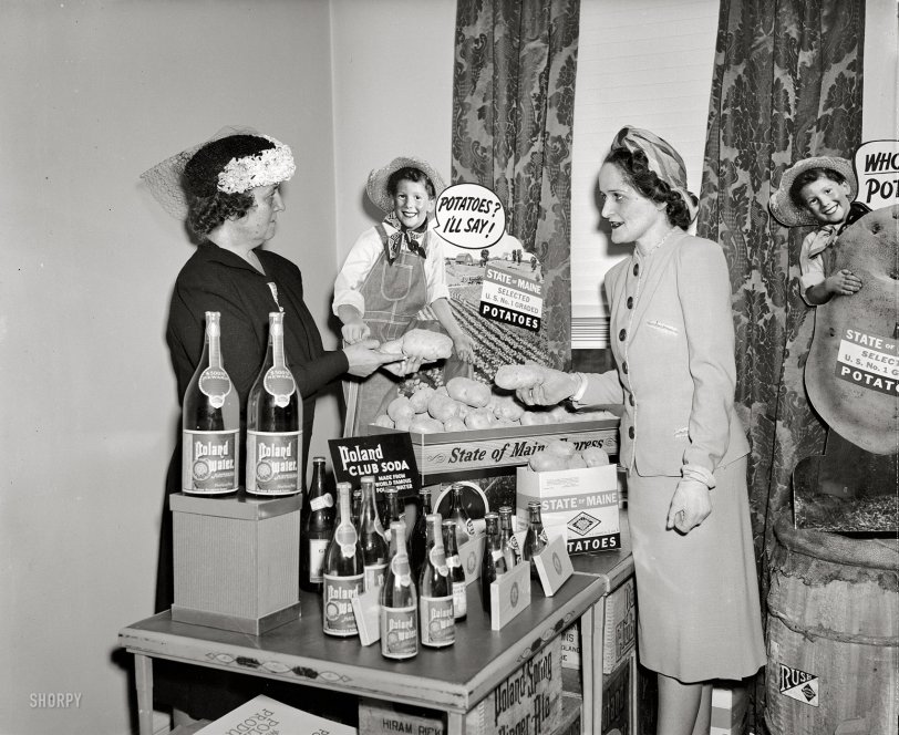Washington, D.C., circa 1940. "Caption missing." A table laden with delicacies from Maine, attended by two ladies who seem to be debating the merits of their respective spuds. Harris &amp; Ewing Collection glass negative. View full size.
