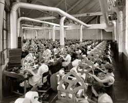 Circa 1925, another scene from the Atwater Kent radio factory in Philadelphia. National Photo Company Collection glass negative. View full size.
Safety first, watch those fingers.No guard covers on the motor belts.
Electrolytic!I always wondered how they made all those capacitors.
Shades of the Triangle Shirtwaist CompanyLooking for the fire exit ... Hmm ... Maybe it's behind the guys in suits?
CapacitatedLooks to me as though they're making capacitors - strips of metal foil separated by an insulating strip - all wound into a cylinder. Used for filtering they allow AC current to pass, but prevent the passage of DC current.
BrazilThis is the first of these shots to remind me of Terry Gilliam's movie "Brazil." Just needs to be a little less well lit, but the machines are as imposing.
Who needs Fire Exits?There IS a fire extinguisher in the room.
(The Gallery, Factories, Natl Photo, Philadelphia)
