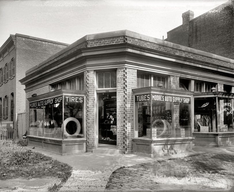 Washington, D.C., circa 1920. "Moore's Auto Supply Shop, 20th &amp; K streets N.W." Next door at Bowie's Tonsorial Parlor: "Hair-Cutting by Electricity." In addition to the usual services of facial massage and umbrella repair. View full size.
