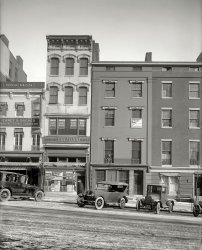 Washington, D.C., January 1922. "517-19 Thirteenth Street." Another of those National Photo portal-to-the-past streetscapes that must have seemed very prosaic at the time they were taken. 8x10 glass negative. View full size.
We mean business
Anita Stewart
Brewood
Eanet &amp; Bacher
Gilda Varesi
Harry S. Levan
Jack Schular
Lew Talbot
Shannon &amp; Luchs
Wineman

ClassThere's a big difference between the car parked in front of the furrier and the ones in front of the print shop and "rooms to let."
Haven't seen a Shannon &amp; Luchs sign, or heard the name, for a long time. 
Two years laterThe Warner Theater would by built on the corner near this location.
Baby Bears! A winter scene - snow on the streets and so cold they wrapped the radiators in blankets.
Completely different todayThis scene is 100% different today.  All those buildings have been torn down and replaced.  The only thing that hasn't seemed to have changed is the road grade.  
Blankets on the car radiatorsNowadays cardboard is used to accelerate warming of the engine in winter. I don't think I've seen blankets.
Also interesting that rear-view mirrors appear not to have been standard equipment, eleven years after being popularized by Ray Harroun, winner of the first Indy 500. Harroun, in turn, had seen one on a hansom cab in 1904.
If only I knewGee, I wonder what will be showing at the Capitol the week of January 8th?
&quot;Winter Front&quot;The Model T coupe has a genuine, designed for the purpose, "winter front". These were common in the days before thermostats, to keep heat in the engine - for the heater if you had one, otherwise for radiant heat. Notice the flaps for regulating the temp. Must have been a cold day since it is all buttoned up.
The touring car has to make do with an old horse blanket.
We have seen a number of cars in these pictures with two plates, one for DC and one for a neighboring state, but the T has two DC plates - one 1921 and the other 1922. Interesting that they have different numbers.
Baby Bear Burlesque

Washington Post, Jan 8, 1922


This Week's Attractions
Capitol - "Baby Bears."

A brand new burlesque show will be presented at the Capitol theater this afternoon when Lew Talbot's "Baby Bears" open their week's engagement. Founded on a snappy French farce, of which Mr. Talbot has purchased the exclusive American rights, the performance abounds in humorous situations and brilliant lines.  A program of more than 20 musical and dancing numbers forms a background for the production.
The chief comedy role is in the hands of Harry S. Le Van, famous on the burlesque stage as a Hebrew comedian. 
Same street in 1943Here is a photo of the same street in 1943, after the Warner Theater was built. You can see the three of the buildings still there in this photo:
Harry&#039;s Final CurtainHarry LeVan's long career in burlesque and vaudeville would eventually lead to work as an early television performer in Philadelphia. Here is his obituary from the Final Curtain notices in Billboard, published on November 24, 1950.
What was the function?Of this type of photo? Was it for insurance purposes, real estate, or some other official documentation?
[Most of these seem to have been taken for the various Washington newspapers or their advertisers, to illustrate news stories or real estate listings. - Dave]
Class IIThe car parked in front of the furrier is a 1920 Buick, either a model K-50 with a 124 inch wheelbase or a model K-47, 118 inch wheelbase.  In 1920 Buick went to straight door handles compared to the loop handles of previous years.
In 1921 Buick revised the entire front of its cars and the hoods and radiators were much higher so that there was a straight line from the top of the radiator to the center of the windshield.
(The Gallery, Cars, Trucks, Buses, D.C., Natl Photo, Stores & Markets)