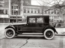 Washington, D.C., circa 1922. "Hudson Coach, Connecticut Avenue Northwest." National Photo Company Collection glass negative. View full size.
FormalwearFor some reason, autos in this style remind me of a dapper young man in tuxedo, tails, and a top hat!
WhitewallsAre those Fisk Cords you're sporting?
Urban LegendThe periodic rumour that the car on the old-style US {$10} bill was a Hupmobile has been strongly denied by the US Mint and the Bureau of Engraving. The original engraver used a composite of many US cars so as not to favour any one manufacturer.
[This information comes from the internet so it may or may not be true]
NearbyYou can see St. Matthew's Cathedral in the background over on Rhode Island Avenue.  Dupont Circle is to the left and Farragut Square is down Connecticut Avenue to the right. The car is not on Connecticut proper but just off. I used to work at 1225 Connecticut, which is just about 200 feet away. I think Jack Pry[e] had a car sales showroom right across the street from this shot, back in the 50s. Some of the buildings across the Avenue are still there, including the building with the bay windows. A great section of Connecticut Avenue. 
ShineThe paint finish &amp; gloss on that car is amazing, even by today's standards.
Hupmobile TriviaAn image of the Hupmobile is featured on the back of the old US $10 bill.
No longer usedThat's lacquer for you.  Looks stunning when it's new.
It&#039;s a Super  6 !!If you zoom in on the hubcaps, you will see that this car is not a Hupmobile at all.  It is actually a 1922 Hudson Super 6 Coach. This body style was a two door, 5 passenger which sold new for $1,795. Due to its immediate popularity, by the end of 1922 they were able to lower the price to $1625.    Hudson pioneered this body style as the first closed car available on the market in the same price level as an open touring car. By comparison, a Hudson Super 6, 7 Passenger Phaeton (an open touring car) sold for $1745.  Hudson Motor Car Co. was the world's largest manufacturer of six cylinder automobiles at this time.
Darn the luckI threw away all my old $10 bills when the new ones came out, so I guess we'll never know.
Famous Super Six ChassisPart of a sign is reflected in the rear window.  Essex and Hudson advertised a 'Coach on the Famous Super Six Chassis' from what I could find in Google.
Perhaps this scene was a street-side auto show of sorts?
Today&#039;s Shorpy PuzzlerWhy does a Hupmobile have hubcaps that say Hudson Motor Car Co.?
[The hubcaps say Hudson Super Six. Because, as you and other sharp-eyed Shorpians have ascertained, this is a Hudson. (I had meant to publish a different photo -- Hupmobile fans will have to wait a few more days.) - Dave]
You could eat off those running boards!The car's finish is incredible. Look at the other cars in the distance, chalky and dull. Schmedleymobiles and Putzmobiles they are. Not the noble Hupmobile.
re: ShineThe paint finish &amp; gloss on that car is amazing...
You started me looking at the reflection. I upped the contrast and stretched it to better see the photographer, his tripod and two companions.

(The Gallery, Cars, Trucks, Buses, D.C., Natl Photo)