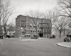 Washington, D.C., circa 1922. "House of Detention, Ohio Avenue N.W." Equipped with a nice playground. National Photo Company glass negative. View full size.
Where Ohio reappearedAs construction of the Federal Triangle was displacing Ohio Avenue, development of the tidal basin/Potomac Park area created an opportunity for it to reappear in a much more casual setting, as Ohio Drive. The Buckeye State fared much better than the Hawkeye State, however. At the peak of Iowa's political power in Washington (with a native in the White House and eleven members in the U.S. House), Iowa Circle became Logan Circle. Iowa's place of honor is relegated to a short, irregular route through Sixteenth Street Heights. 
Go a bit too FarAnd here's your home away from home!
Where did you go, Ohio?"In the 19th century, an Ohio Avenue did exist just south of and parallel to Pennsylvania Avenue. The avenue was obliterated in the early 20th century by the Federal Triangle complex proposed by the 1902 Senate Park Commission Plan. The United States Department of Commerce and the Internal Revenue Service currently sit on the path of the old Ohio Avenue."
Both DC and Maryland TagsNote that the cars carried both DC and Maryland tags. There was not reciprocity between DC and Maryland at the time. My parents had stories of swapping tags at the DC line.
Or elseSo that's the place where my mom was going to send me if I didn't straighten up my act. Although back then they called it reform school. The bars on the windows lend a nice homey touch. BTW, I was pretty sure she wouldn't do it -- but not sure enough to call her bluff.
What is this House of Detention? Readers might ask: "What is this House of Detention, who is detained there, exactly where is it, and when was it opened?" Well, let's ask Mrs. W. C. Van Winkle ...
HOUSE OF DETENTION.
STATEMENT OF MRS. W. C. VAN WINKLE, DIRECTOR OF HOUSE OF DETENTION AND DIRECTOR OF WOMEN'S BUREAU, POLICE DEPARTMENT.
Mr. DAVIS. We started this morning to go over the estimates for the House of Detention; and there are quite a few things here that even the commissioners, I am sorry to say, did not fully understand: and the suggestion was made that you come before the committee and fully inform us on certain matters. Will you give us a short description of the activities of the House of Detention, what part you play in them, etc. ?
Mrs. VAN WINKLE. You know what the building is used for, do you not?
Mr. DAVIS. I think I do; but perhaps you had better put it in the record. You know there are 435 Members of the House, and they do not know all that is to be known about these, things.
Airs. VAN WINKLE. The House of Detention is a shelter for all juvenile delinquents. A delinquent in the District is a child under 17. That means that both boys and girls are sheltered there. All female offenders over 17; all stranded women and girls; all fugitives from institutions and from parents.
Mr. DAVIS. Regardless of age?
Mrs. VAN WINKLE. No, not of male prisoners over 17; but regardless of age of fugitives from institutions if they are females: and also little children who are fugitives from home. All the wards of the Board of Children's Guardians who are awaiting a home, or pending trial in the juvenile Court, and such cases as the judge of the Juvenile court determines must wait with us, even after trial in court, until sentence and final disposition.
Mr. DAVIS. You are connected with the House of Detention in what way ?
Mrs. VAN WINKLE. We formerly had policemen detailed to the house. When we moved into the new house at Fifteenth Street and Ohio Avenue on September 1, 1920, the chief of police detailed me as director of the House of Detention. He made me directly responsible for the care of the children in that house and for the discipline and direction of the employees.
Mr. DAVIS. Do you have to do with the female policemen?
Mrs. VAN WINKLE. I am Director of the Women's Bureau of the Metropolitan Police Department.
Soap Box Derby on steroidsCan any Shorpsters  identify the vehicle sitting at the left rear corner of Juvie Hall?  Also, the awnings on the windows are a nice, homey touch on a pretty grim place.
Emergency HospitalDoes anyone know if this building was previously used as the Emergency Hospital, which was described as standing at 15th and Ohio Avenue?
Mystery CarThe car at the left corner is a Ford Model T speedster. Looks to be home-built. Cars like this were common in the 20s and 30s. Usually built by young men, they were considered quite rakish.
Any and all help wanted.Folks,
I am a novice historian of the Washington D.C. metropolitan Police. I would be very grateful for any information that could be forwarded to me. My site is;
http://www.dcmetropolicecollector.com
My e-mail address is guinness0298@yahoo.com
Be Safe,
Chuck
(The Gallery, D.C., Natl Photo)