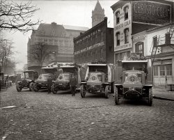 1924. Piggly Wiggly trucks in Washington, D.C., at the Christo Cola Bottling Co. View full size. National Photo Company Collection glass negative.
Old Post  OfficeI found an address for Christo Bottling Co. at 209 Eleventh Street NW.  This places it smack in the middle of what we now call Federal Triangle.  Clearly visible in the background is the spire of the only remaining 19th century building in the area: the Old Post Office pavilion. 
Christo ColaEvery bottle wrapped in 300 yards of pink silk!
Piggly Wiggly MacksThat's a lot of lettuce. I see some taters too. Great photo.
Old Post OfficeNot just the spire - the main body of the building is visible, gigantic glass skylight and all.
See http://www.oldpostofficedc.com/ for the Old Post Office as it is today. The camera is looking roughly West, the spire at the front of the building overlooks Pennsylvania Avenue with 12th Street to the far side and what would be 11th Street on its near side - but even in this photo as today, it doesn't look like 11th Street is there. The trucks are lined up along along C Street, which is also not there today.
At an educated guess, that would put the buildings in the middle distance, and maybe the cola factory, exactly where the Internal Revenue Service building is today.
Love the...Love the horse-drawn wagon followed by cars!  It was still a transitional period. I am addicted to this site!  Thanks for the great pics.
TruckinThat's one well maintained fleet.
White &amp; MacksThe truck on the far left is a White, and it is a circa 1920 Model 20.
The other four trucks are Mack AC "Bulldogs" that look brand new (although the one on the far right has not had its lights and horn installed).  ACs were available from 1916 - 1938 and the chassis were rated from 3 1/2 - 15 tons.  All had four cylinder gasoline engines.  
The larger radiators  easily identify these ACs as being built late 1922 or after.  Another feature which was introduced at the same time was a 4-speed transmission.
A total of 40,299 Mack ACs were produced from '16 - '38.
(The Gallery, Cars, Trucks, Buses, D.C., Natl Photo, Stores & Markets)