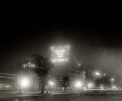 Washington, D.C., circa 1918. "World War I. Food Administration electric signs, 7th Street and Pennsylvania Avenue N.W." National Photo Co. View full size.
Fog or Photo?Are the halos around the lights caused by atmospheric conditions, or are they photographic phenomena?
Temperance Fountain MoveThat is the Temperance Fountain.  I think it was moved when the Metro line was built under Seventh Street.  I always though it was ironic that the Temperance Fountain stood in front of the Apex Liquor Store.
The Jesus signI think the Jesus sign says, "Jesus the light of the world." I think it would only be a controversy if it were on a public (government-owned) building--and, if it were on such a building, it should be a controversy.
Temperance FountainThe cement-canopied monument right in front of the Apex building looks like the notorious Temperance fountain (with its twisted fish and green-copper heron). If so, it seems to have moved a bit north since this photo was taken.  
The Word Will Shine SteadilyWashington Post, March 25, 1910.


ELECTRIC SIGN FOR MISSION
Great Letters Will Flash "Jesus, the Light of the World."
&nbsp; &nbsp; &nbsp; &nbsp; The Central Union Mission will soon erect on the roof of the mission building an immense electric sign bearing the words "Jesus, the Light of the World."
&nbsp; &nbsp; &nbsp; &nbsp; The letters in the word "Jesus" will each be between 12 and 14 feet in height, and the word will shine steadily. The phrase "The Light of the World," in which the letters will be about 8 feet in height, will flash alternately.
&nbsp; &nbsp; &nbsp; &nbsp; It is the intention of committee which is conducting the work to have the cost of the sign, which will be about $700, borne by the Sunday schools of the city, and the young people's societies of the different churches will be asked to contribute to the expense of maintenance.

Mexico City - 1962Its a long story, but I found myself in Mexico for Christmas and "Three Kings Day" in 1962 and the church near where I was staying had put out a bright red flashing neon sign as their holiday decor which simply said "Ole'Jesus".  
Regardless......it seems the Army outranked Jesus...
Religious expressionYou can put a sign up saying "Jesus Loves the World" anywhere you want, as long as it's not on public (city, state, country) owned property. You could also put up a sign which says "Allah Loves the World", or anything else you want to say. Let's not make controversies where they don't exist. Ain't America great?
UnsignedThe building today.
View Larger Map
Heavenly LightThe sign below the name of Jesus reads, "THE LIGHT OF THE WORLD." It is taken from John's gospel (8:12), where Jesus says, "I am the light of the world. He who follows Me shall not walk in darkness, but have the light of life."
Calling Jay WardAm I the only one who is old enough that this brought back memories of the Rocky &amp; Bullwinkle Show closing credits?
Central MissionCentral Union Mission still exists in Washington and still has a religious message in big letters on its building.  There is no controversy about it.  The only controversy is from the gentrifiers who have moved into the neighborhood and don't like having a homeless shelter nearby.
The sign to the leftDoes the sign to the left say "Jesus Loves the World"? Sadly in today's America, that would be a controversy if it wern't in front of a church.
Food or Army?Don't waste the food or don't waste the Army?
re: Fog or Photo?It's a photographic effect called halation, in which the light passes through the emulsion and is reflected back onto the rear of the emulsion by the glass plate or film base, as the case may be.
Sometime later (1920s?) manufacturers placed an anti-halation coating on their plates and films.
(The Gallery, D.C., Natl Photo, WWI)