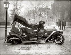 Our third look at that circa 1917 car wreck at Massachusetts Avenue and 21st Street N.W. in Washington. As with so many of these old glass negatives, mold is colonizing the thicker parts of the emulsion. The result is an accident scene that looks like it's been dusted with flour. National Photo Company. View full size.
HonkWhile the horn is certainly cool, it is not a Klaxon. Klaxons are electric or hand powered. This could be a Rubes horn.
WrecksAll these early car accidents make me think surely there were carriage/wagon wrecks. Any pics of those?
[Not that I've seen. But there are plenty of newspaper accounts of "runaway teams," which seem to have been a major hazard. - Dave]
BottleWhat's that bottle for on the running board? If it were 50 years later or more, I'd say it's a fire extinguisher, or it's an NOS bottle and this heap piled up while draggin' fer pinks.
[It's acetylene gas for the headlights. - Dave]
The CarHas anyone identified the make of this auto?  I didn't see a manufacturer's logo. It seems to be right-hand drive with controls outside the cab -- probably emergency brake.  That great horn could be an add-on.  With the worn and slightly tattered top it probably is dated sometime earlier than 1917.
[The hubs are embossed with what looks like the word "Eagle." Or maybe "circle." There's one more photo of this car left to post. - Dave]

Below, the 1907 New Eagle, a four-cylinder car made in England.

KlaxonThat horn is awesome.
EagleDave, I think you got it.  Other details (radiator cap, horn) match nicely.  Well done.
Eagle Electric Company?The radiator shape of the New Eagle and the car in the accident are vastly different.  The radiator shape of the New Eagle is completely round at the top with no variation in the thickness of the grill surround.
The New Eagle that was made in Cheshire, England was only made from 1901 - 1907, and it seems very unlikely that any were imported into the U.S.  There are also differences in the horn and side lights.  A short history of these cars is here: http://www.3wheelers.com/eagle.html
Looking closely the hubcap looks like it might spell out "Electric Eagle Co." which was a brand made in Detroit, Michigan in 1915.
Also of note, District of Columbia license plate numbers 1 - 83 from 1907 - 1917 were issued to various automobile companies for demonstration purposes.  Perhaps numbers 24 and 26 were out together on a demonstration ride.  
Automobile1909 Columbia Model 29 Four-Passenger Toy Tonneau
(The Gallery, Cars, Trucks, Buses, D.C., Natl Photo)