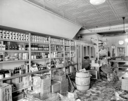 Washington, D.C., circa 1935. "Food supplies, interior of D.G.S. store." One of several District Grocery Stores in the capital; there's a P Street address on the burlap sack. The White Rose brand seems especially well represented on these shelves. 8x10 acetate negative, National Photo Company. View full size.
Bug juiceAnybody else have a family history of calling Lea &amp; Perrins "bug juice"? Also, re: sawdust in butcher shops: aid in absorbing fluids you didn't want to think about.
Lea &amp; Perrins Worcestershire SauceThat packaging has hardly changed an iota in all these years.
Still familiar namesMueller's
Aunt Jemima
French's
Campbell's
Domino
Kraft
Lea &amp; Perrins
Wheatena
Oxydol
Sawdust MemoriesMy father worked in butcher shops when I was young and there was always sawdust on the floor. I guess that made it easier to clean up or something.
Junket TabletsMake milk into DAINTY DESSERTS. Resting atop a box of Steero bouillon cubes.
How terrific this isto see all of those oldtime products on the grocery shelf! Representative packages or cans of just about all of these items might have been found on my mother's pantry shelves back in 1940. It's especially neat to see that box of Oxydol ("Oxydol's Own Ma Perkins") but where is a box of either Rinso or Super Suds? ("Rinso White, Rinso Bright, Happy Little Washday Song", and "Super Suds, Super Suds, Lots More Suds with Super Suh-uh-uds").
[There is a big box of Chipso here. - Dave]
Wire Baskets in this StoreDuring the same decade, in Oklahoma City, an inventor put wheels on some wire baskets and called them shopping carts.  
Seeman Brothers&#039; Brand Folks in New York and New Jersey will still recognize the White Rose brand. It's the independent label for the Seeman Brothers wholesale grocers, est. 1886. Their website says they still offer 18,000 items in the New York area, dominating the market. It's all based on their unique fermented White Rose Tea.
During my childhood in '50s South Florida, displaced New Yorkers flocked to New York style grocers on Miami Beach to get that tea which was as strong as coffee.
A detailed history here.
Disease and pestilenceLooks like they weren't expecting a visit from the health inspector.
White RoseStill around. From their website:
Today, White Rose is the largest independent wholesale food distributor in the New York City metropolitan area, which in turn is the largest retail food market in the United States.  White Rose Food serves supermarket chains, independent retailers and members of voluntary cooperatives, providing more than 18,000 food and nonfood products to more than 1,800 stores from Maryland to Connecticut. The highest concentration of these customers is in the five boroughs of New York City, Long Island and northern New Jersey.
Tea BaggersThe White Rose Food Company is still with us. They're most popular product is White Rose Tea. Based in New Jersey, they claim to be the largest food distributor in the NYC Metro area.  The 125 year old company has an interesting story, you can read it on their website, www.whiterose.com/, 
Hello Jell-OJust noticed Jell-O hiding in there too. Both behind and to the right of the French's Mustard.
Our 14th Anniversary Sale!DGS celebrates 14 years at their over 250 stores in the Metropolitan Washington area. Just phone in your order!
(Despite the date, I doubt anyone phoned-in a birthday cake order for Der Führer.) 
More still familiar namesAdd Jell-o to the list
One of the original house brandsWhite Rose "house brand" products have been around for more than a century, and the company is still around: http://www.whiterose.com/history.asp
Key in the doorI love the fact that the key to the door is tied to the doorknob with a piece of string.  Hard to misplace that way.  Must have been lost previously so someone "fixed" that.
Before there were supermarketsThis photo is representative of one of my favorite subjects: the old-time Ma and Pa stores. In it, you can see the evolution of retailing, product packaging, and brand name history.
This reminds me of the corner neighborhood stores in Baltimore. The blocks of rowhouses were frequently punctuated with such corner stores. In my neighborhood, in a two block area, the four corners had a butcher shop, a grocery, a bakery, and a drugstore/soda counter. These existed into the early 1960s.
Of course, today's supermarkets are a cleaner, superior shopping experience, but a certain flavor has been lost - can you remember the smell of a real bakery shop?
Junket!I haven't thought of Junket in decades. My grandmother made it for my sisters and I all the time when we were below the age of 8, but it came in packets, not tablets. It made something akin to a blancmage, although I don't think you could ever have a Junket win Wimbledon.
I believe you can still find it if you're lucky.
District Grocery StoresDGS was a buying consortium of small independently owned groceries in the Washington area.  They were a bit more expensive than the larger chain stores (A&amp;P, Sanitary - later Safeway, etc).  However, you could phone in your grocery order and it would be delivered within a hour or so.
More sawdustHere, it might have been used to add flavor and palatability to some grungy looking celery.
Re: Sawdust50+ years ago I worked in supermarket meat markets.  Sawdust was put on the floor to prevent slipping.  It was spread about an inch thick.  At the end of the week it was swept up, the floor cleaned as necessary, and new sawdust put down.  In general, health regulations today prohibit using sawdust.
Celery gone overLooks like the celery has started to rot and the store manager is mad about it!
Aunt JemimaWhy would some boxes have Jemima's picture, and not others? Another great mystery. Anyway, this youngster knows what to do with the box. Born in 1927, she has achieved fame and fortune as my Aunt Libby.  Taken over-at-the-house-on-the-hill in Hamlin, West Virginia.
[The box in your adorable pic is a jumbo size container of pancake flour. The one in our photo holds 24 small boxes, each with Aunt J's picture on it.  - Dave]
Wire baskets on wheels?Shopping carts?  In Oklahoma today they are called buggies.
HodgepodgeIt's interesting the mix of products on the shelves; no grouping of veggies in one area and soups in another and sauces in yet another.  Were prices for the items placed in those holders along the edge of the shelves? 
Here&#039;s the Junket, but Where&#039;s the Beef?Junket was (and still is) a common way to use slightly curdled milk to make custards; and it's also used by cheesemakers.  My mother used it whenever the milk was just about to go bad.  Growing up in the Great Depression, anything that could be done to salvage food items was considered priceless.  As for Steero bouillon cubes (later Herb-Ox?), they were used for flavoring soups and stews whenever actual meat was scarce/unavailable.  Also, the broth was considered an early form of "comfort food".  During WWII, my father and uncles received jars of Bovril, the U.K. equivalent of Steero in their Red Cross packages.  It got traded amongst the men, almost as much as cigarettes and coffee.
(The Gallery, D.C., Natl Photo, Stores & Markets)