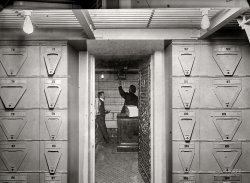 1914. "Treasury Department, Office of Comptroller of Currency -- bond vault. Contains bonds to the value of $900 million securing government deposits and postal savings fund." National Photo Co. glass negative. View full size.
Smoke BreakLooks like he's reaching for the fan switch before they light up.
Then and Now$900 mil would be +/- $20,360,700,000 in 2011 according to the inflation calculators.
US Postal Savings, existed from January 1, 1911 until July 1, 1967. It was still big in Europe the last time I looked.  This system was set up by the US Government to act as a saving account for anyone too poor to have a saving account or lived too far from a bank.
Two weeks worth of warThe direct cost of U.S. involvement in WWI was roughly $23 billion, from the U.S. declaration of war in April 1917 until the end of the war in June 1918. (Source: "Direct and Indirect Costs of the Great World War" 2d ed. [Washington 1920] by Ernest L. Bogart.)  So the $900 million represented here covered the cost of two weeks of the looming "war to end all wars."  
Glass ceilingWhat's going on with the top of the glass plate?  At the top, it appears there's part of another picture, and the I-beams and everything else are abruptly cut off.
[It's the very top portion of another shot taken at the Treasury Department at the same time. At some point in the past, prints were copied to glass negatives and these two happened to be stacked unevenly atop one another.]
Postal SavingsFrom what I've been told about my coal miner grandfather, he used the postal savings exclusively.  He distrusted banks, saying that (back then) there were any number of counters for making deposits, but only one for withdrawals. According to him, they even knocked a hole in the wall so you could put your money in at night. 
(The Gallery, D.C., Natl Photo)