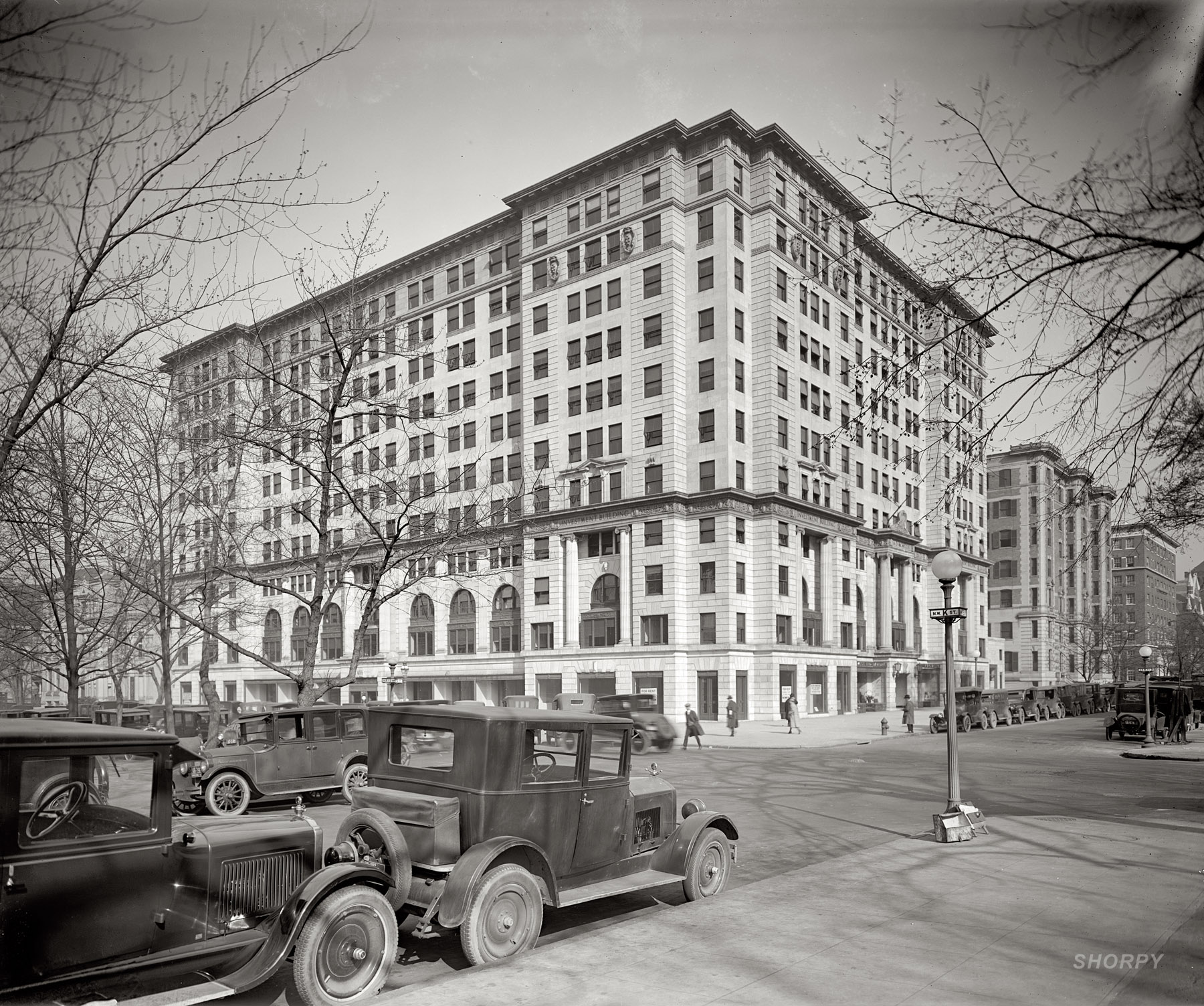 The Investment Building in Washington at 15th and K Streets in 1925, shortly after its completion. Home to the barber shop seen here yesterday, the Investment Building was touted as being the first big office building in the East with an underground parking garage. Ten years ago it was torn down and replaced with a new structure designed by Cesar Pelli, who used the original limestone for the street-facing facades, which were propped up during demolition with a framework of steel girders. Except for the modern superstructure peeking over the top, the new Investment Building looks pretty much like the old one. National Photo Company Collection glass negative. View full size.