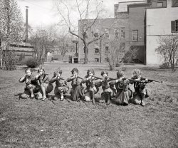 1925. "Girls' rifle team, University of Maryland." National Photo. View full size.
Better Than the MenNote that the event where the "girls" out-shot the men occurred exactly 84 years ago today, February 10.


U. of M. Coeds Defeat Men in Rifle Match

Co-eds of the University of Maryland Proved themselves better marksmen than the male students at the institution in a rifle match Tuesday at College Park, according to a "post-mortem" examination of the score today.
The score showed the men had made a desperate effort to avoid defeat, registering 497 marks out of a possible 500.  But the female of the species proved "more deadly than the male" with the rifle - at least the girls came off with a score of 499.
The campus yesterday was a dismal place so far as men were concerned.  Vainly they tried to show resignation, or smile or treat the whole affair as an accident.  It was hard to realize and acknowledge that girls had beaten them.
However, the vanquished team had forgotten that its triumphant adversaries had a reputation for marksmanship to preserve in the contest Tuesday.  The reputation was won when the girls gained third place in the nation-wide intercollegiate competition last year, although it was only their second year of shooting at targets.
The five girls who made the best scores were Miss Thelma Winkjer, of Washington, captain of the team, who scored 100; Miss Helen Beyerle, of Baltimore, a former pupil at Western High school, 100; Miss Rebecca Willis, of Washington, 100; Miss Julie Louise Behring, of Washington, 100; and Miss Mary Harbaugh, of Washington, 99.

Washington Post, Feb 12, 1925 



Girl's Sports Making Big Strides at Maryland University

The rifle team has established an enviable record at which both the girls' and men's teams in all schools will shoot for some time before equalling.  Every match shot this year has been won by the College Park girls, including a shoulder to shoulder affair with the boy's team, and there is every reason to believe that they will finish the schedule without defeat.
...
The team has defeated the University of Washington and West Virginia, Agricultural College of Utah, University of Chicago and Drexel Institute in telegraphic matches.  Those still to be shot are Syracuse university, universities of Arizona, Vermont, Illinois, Delaware, and Michigan Agricultural college.
The high scorers are the Misses Rebecca Willis, Anna Dorsey and Helen Beyerle. Team members are the Misses Thelma Winkjer, captain; Mary Harbaugh, manager; Betty Amos, Grace Coe, Anna Dorsey, Alma Essex, Julia Louise Behring, Mary Jane McCurdy, Rebecca Willis, Elizabeth Flennor and Helen Beyerle.
...

Washington Post, March 29, 1925 


Bullet pointsThe girl on the left maybe doesn't want her picture taken. Hope the lens cap was bulletproof.
New WaveThis is a great showcase for one fad of the 1920s and 30s -- marceled hair.
You go girls!This is one of my favorite pictures of late--especially in combination with stanton_square's articles.  That poor defeated men's team--I wonder how long it took to live that down?
The third girl from the right looks like she's really enjoying the photo shoot.  I bet they'd be an interesting group of ladies to hang out with.  It looks like a few of them are wearing pants (especially the girl second from left), though possibly they could just be carefully arranged skirts.  How big of a stir would wearing pants have made by this time?  Or was it sort of accepted by this point?
Girls Gone Rational"Rationals" were a form of women's athletic clothing worn while taking part in outdoor sports. Most rationals were a combination of a skirt and bloomers (see the woman third from the right), but some were just bloomers (fourth from the right) -- the latter could also be known as simply knickerbockers, and were at first glance indistinguishable from them.
Like other forms of athletic wear of the time, they would not be worn as street clothing.
At this point, women of fashion are not wearing trousers for day wear quite yet. It'll another seven or eight years before Marlene Dietrich, Katharine Hepburn, etc. begin to make trousers fashionable for all but women deliberately dressing as men.
She&#039;s just not that into youThis reminds me of a bad breakup I had in college.
Where on campus?I went to UMD - wish I could figure out where on the campus this was. It was after the big fire, so the buildings in the pic should still be there. Would love to see more of these around campus if there are some!
[This is probably in Washington. It's the same location as in this photo of the Drexel rifle team. The two teams met in March 1925 at George Washington University's Corcoran Hall rifle range. - Dave]
There&#039;s One!"Girls, swing 'round!  There goes one behind us!"
Firing SquadThey're not posing!  Their hairdresser is tied up to a pole just off to the right of the photographer....
No SurpriseWhen my daughter started college, her dormitory floor's Resident Assistant held a floor meeting, and asked the residents what they'd done over the summer.  The one that I remember was the one who was instructing riflery at West Point.
Wrong school citedThis photo is a scene on the campus of the George Washington University, in Washington, Dc.  It is not a view at the U. of Maryland.
[Confused? This is the University of Maryland rifle team, competing in Washington at GW. - Dave]
(The Gallery, Natl Photo, Sports)