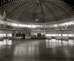 "Arlington Beach." Circa 1925, the dance pavilion at the amusement park across the Potomac from Washington. National Photo glass negative. View full size.
Replacing bulbsAn interesting structure for sure, requiring a lot of skilled labor to piece together all those angle joints. 
It appears this was lit with a series of small bulbs running up the underside of each truss. Probably gave a nice atmosphere but I wonder how they got up there to replace them which must have had to be done often. 
Does this structure still exist?
[Torn down in 1929. - Dave]
Disco Ball!And here I thought Disco balls dated from the Disco era. I wonder if that ball actually managed to survive into the Disco era, somehow.

In case anybody wants one...those mirrored balls are still available for $34.99 at the party store. And I thought that we psychedelic hippies invented them. 
Dance pavilionsWhat memories. I think there were dance pavilions up to WW2. We would drive out from Detroit to Walled Lake with its dance pavilion and really enjoy the dancing. This was the summer of '41 before Pearl Harbor and it has not been the same since.
Lions and Rotarians, and Shriners, oh my!I like the banners of all the lodges surrounding the ceiling. 
I can&#039;t imagine..the carpentry/framing skills required to build something like this.With all the odd angles and radial trusses,must of been quite a challenge, even for true craftsmen.
Room for 1,000

Washington Post, May 23, 1925 


Arlington Beach, Many Attractions Added,
Opens Today
Bathing Facilities Enlarged;
Dance Pavilion to Accommodate 1,000

With many added attractions, Arlington beach, Washington's only bathing beach, located at the south end of the Highway bridge, will be opened today.  With the Tidal basin closed, the bathing at the beach will be one of the leading attractions, and realizing this the management has announced that 2,500 new bathing suits, 4,000 new steel lockers and several shower baths have been added.
The beach this year will be operated under the management of Jesse Thomas and Lloyd Schafffer.  Mr. Thomas said no expense has been spared to make the park one of the leading amusement places of Washington this year.
The leading Washington orchestra will furnish music for dancing in the pavilion, which will accommodate more than 1,000 persons.  While the roller coaster will not be ready for the opening, work is being rushed, and it will be completed in a few days.
Mr. Thomas said that the management this year will specialize in making Arlington beach a family resort and a place for all-day outings for clubs, schools, lodges and church societies.  Ample room has been provided for parking.



Thanks again, Shorpy!Once again, you have revealed a gem from the past. I marvel at all the man hours and wood that went into the construction of this big ol' barn.  I can't help but wonder how the music sounded as it bounced off this cavernous structure with dancers on deck. I believe Brunelleschi himself would appreciate this dome.
Breaker, breaker, for a Walled LakerAh, yes, good old Walled Lake:

See it larger here.
(The Gallery, D.C., Natl Photo, Sports)