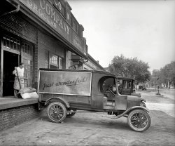 Washington, D.C., circa 1925. "Ford Motor Co. truck, John H. Wilkins Co." National Photo Company Collection glass negative. View full size.
And NowIt's an AutoZone parking lot.
View Larger Map
Lizzies!Five Model T Fords in one shot! Must have been fun to hear them trundle off to work in the mornings...
Jeff
Interesting Parking BrakeI like the rock in front of the rear wheel.
Is that Robert De Niro??I am not kidding. The guy loading the truck is De Niro.
Rhode Island Avenue NEIt appears that this was on the 500 block of Rhode Island Avenue NE - the John H. Wilkins Co. is referenced to have been located at 525.  Nothing remains today.
View Larger Map
Interesting parking brake on the truck.Note the half-brick under the right rear wheel, with the solid tire.  
What was "just wonderful" on the side of the truck about?
[Coffee. If you look closely you can see lettering. - Dave]
If we look carefully, we might findthat little rock that serves as a brake.
Parking Brick is SetA high-tech method for ensuring the truck stays put.  Still in use today.  It's hard to improve on perfection.
DeNiro&#039;s doppelgangerYou talking to this bag of sugar?
NapsterLooks like the guy in the next truck over is taking a little snooze.  
Wilkins CoffeeThe Wilkins Company slogan was "Try Wilkins Coffee - It's Just Wonderful!"  From 1957 to 1961 Jim Henson made 179 TV commercials for them in his pre-Muppet days.  Dozens of these can be found on the internet.
The coffee was reputed to be quite good and although it disappeared from DC area grocery stores in the mid-1990s, it supposedly is still available through Royal Cup Coffee's commercial and office service sales department.
About the time this picture was taken the John H. Wilkins Co. was being charged by the Federal Trade Commission for unfair methods of competition.  They were in the habit of leasing or loaning coffee urns to customers without payment except for an expressed agreement that the customers would purchase all their coffee and tea from Wilkins.  The charges were later dropped.
Also about this time period the Wilkins Co. bought a new fleet of trucks that were painted white.
KermitWilkins Coffee adverts on TV in the 1950s made Kermit the Frog famous and helped launch an empire. 
Highway RobberyJohn H. Wilkins started in the wholesale grocery business but eventually specialized in roasted coffee, forming the Wilkins Coffee Co. in the mid 1920s.  Wilkins Coffee, a long-lived Washington institution, is now remembered on the internets for early TV commercials featuring a young puppeteer named Jim Henson.



Washington Post, Dec 12, 1924 


Robber Takes $1,200 from Truck Driver
Wholesale Grocery Delivery Man Held Up
on the Highway Bridge

A robber held up a truck driver and robbed him of $1,200 on the Virginia side of the Highway bridge shortly after 6 o'clock last evening.
C.F. Chenault, driver for the John H. Wilkins, wholesale grocer company, 519 Rhode Island avenue northeast, was returning from Alexandria after having delivered a large quantity of groceries there.  A colored "jumper" was riding alongside him.
The robber had leaped on the running board of the truck before the two men saw him.  He ordered Chenault to stop the truck and hand over all the money he had.  This Chenault did and the bandit fled in the direction of the river.
Arlington county authorities and the local police are investigating the holdup.
Re: Is that Robert De Niro??I agree it is DeNiro in "Back to the Future" 1985. The mole is even on the correct side and position of the face. 
Rhode Island AvenueWhat a great photo.  It could only have been made better if the photographer had caught a streetcar going by on its way to Hyattsville and beyond.
Chief Navy Coffee Roaster

Washington Post, Jul 26, 1960 


Mrs. John H. Wilkins Dead;
Widow of Coffee Firm Founder

Mrs. John H. Wilkins, 77, widow of the founder of the Wilkins Coffee Co., died Sunday at her home, 3411 Woodley rd. nw., after a long illness.
Mrs. Wilkins, born Aida Seal in Washington in 1883, was a member of a sixth-generation family here and a descendant of the Seal family that settled in Maryland and Virginia in the late 17th Century.
One of her relatives, George Washington R. Seal of Winchester Va., was among the first to manufacture artificial gas for use in lighting that city.  Another ancestor, Samuel Douglass, settled in a community originally known as New Scotland Hundred in Charles County, Md, which eventually became Georgetown in Washington.
At the time of her marriage to Mr. Wilkins at the turn of the century, her husband owned a small retail specialty shop at 1921 14th st. nw., and sold coffee, tea, butter and eggs.  From a small roaster and five bags of green coffee, Mr. Wilkins expanded his business into a million-dollar corporation by 1947, the time of his death.
Mrs. Wilkins leaves a son, John H. Wilkins Jr., current president of the coffee company; a granddaughter, Mrs. Cooley Kennedy, and a great granddaughter, Christina Lyn Cooley, all of 4200 Cathedral ave. nw.
A private funeral service will be held at 2 p.m. Wednesday at Gawler's Chapel, 1756 Pennsylvania ave. nw., with interment in Rock Creek Cemetery. 


Washington Post, Apr 1, 1967 


John H. Wilkins Dies at 65;
Headed Coffee Company Here

John H. Wilkins Jr., 65, chairman of the board of the Wilkins Coffee Co., died of a heart ailment yesterday at Doctors Hospital.
Mr. Wilkins had been chairman of the company's board since last June, and had been its president for 19 years prior to that.
Born here, he was a fifth generation Washingtonian.
After graduation from Babson Institute of Business Administration, in Wellsley, Mass., he joined his father, the late John J. Wilkins Sr., in his wholesale coffee and grocery firm here.
In 1923, a fire destroyed most of the firm's warehouses.  Mr. Wilkins persuaded his father to terminate his grocery business at that time, and from then on, the firm's efforts were concentrated on processing coffee.
Wilkins Coffee Co. built its main plant in Landover, Md., in 1965-66.  The company also operates plants in Philadelphia, Harrisburg, Pa., Baltimore, Richmond, Norfolk and Raleigh, N.C.
Mr. Wilkins is also one of the four founders of Tenco, Inc., which became one of the largest processors of instant coffee in the world.  Nelson Rockefeller, now governor of New York, was active in the firm before it was sold to Minute Maid Orange Juice Corp., which was later bought by Coca-Cola Corp.
During World War II Mr. Wilkins served in the Navy as an activated reserve officer.  For 26 months he served at Pearl Harbor, and then was assigned to be chief of the Navy's coffee roasting plant in Oakland, Calif.  After about four years of service, a heart condition forced him to resign.
Mr. Wilkins was especially active in the Washington Heart Fund, where he headed the first Greater Washington fund drive and was honored as the fund's first life member.
He was also a member of the New York Coffee and Sugar Exchange, National Coffee Association of the U.S.A., Metropolitan Washington Board of Trade, Merchants and Manufacturers Association of Washington, National Association of Manufacturers, Army and Navy Club, University Club and National Press Club.
He is survived by his wife, Ruth M., of the home address, "Chestnut Lawn," near Remington Va.; a daughter, Lyn W. Kennedy of Washington, and a granddaughter.

I am unable to find any notice in the Post regarding the death of John H. Wilkins, Sr., in 1947.  Are the pages recording his death are missing from the digital archives or was his death so scandalous that it went unreported in the newspapers?
[He had the temerity to expire elsewhere. Below, item from 6-14-47 - Dave]
(The Gallery, Cars, Trucks, Buses, D.C., Natl Photo)
