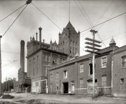 Arlington Brewing Co. circa 1920. An 8x10 glass negative that would leave your fancy-schmancy digtal SLR crying for its mommy. View full size. Nat'l Photo.
DetailWhen your pixels are molecular sized you can usually get more detail.
[The obvious difference is that in an SLR the verticals would be tilted inward toward the top because you have no perspective control. The "pixels" would probably be around the same size or a little bigger than a CCD pixel (a 12-megapixel SLR can capture far more detail than a 35mm film camera). But there would be many more of those pixels -- the image sensor in an SLR is around one square inch; an 8x10 glass plate is 80 times as big. - Dave]

Watch That First Step!Those doors on the second floor look pretty dangerous!
Prohibition VictimIf this photo was shot in 1920, the Arlington Brewing Co. had already been out of the beer business for four years. The state of Virginia went dry in 1916, and the brewery was located in Roslyn Virginia. During Prohibition it produced a soft drink called Cherry Smash. It didn't reopen after the repeal of Prohibition in 1933 and was used as a warehouse until the building was torn down in 1959 to build a new hotel. Presumably the hotel resembles a box (doesn't all 1959 period construction).
[Key Bridge Marriott. - Dave]

HayloftThat "second floor door" is where hay was stored in the stable. The exposed beam above the door is a pulley post. Wagons loaded with hay and feed would drive up and their loads would be lifted into the hayloft using block and tackle. When it was time to feed the horses, hay was dropped down a chute or opening into the stall cribs in the stable below. The iron gate is for equine access.
Arlington Brewing Co. probably used big draft horses - Belgians, Percherons, Clydesdales or the like. Barrels of beer are heavy!
And, it&#039;s still hereNot only is it incredibly detailed, but more importantly, it's still here. This negative survived by just being stuck in a box somewhere in a reasonably favorable environment. Do nothing over the next 88 years with the digital image you take today and see if anybody's able to view it in 2096.
Also, a new Shorpy pastime: Count the Bricks!
Does that faded sign say"Wiener the perfect beer?"  "Wiener the Purified Beer?"
Can't quite make it out.
[Pure. - Dave]

Sharp"An 8x10 glass negative that would leave your fancy-schmancy digtal SLR crying for its mommy. "
To say the least.
An Excellent PointThis worries me too. When we cleaned out my Great Grandmothers house after she died we found a huge album of photos taken in Alaska between about 1880 and 1920.
I'm not sure what, if anything soomeone would do if they came across a bunch of my backup dvd's or and ancient external hard drive a hundred years in the future.
Hopefully technology will settle on one photo format soon and stick with it.
Those TracksThe details are beyond anything that a digital camera will record. As a rail fan, I noticed the trolley wire frog in the top left hand corner of the photo. While there does not appear to have been a siding to the building, the area was served by an Interurban electric railroad. By the mid thirties, most Interurbans were being abandoned. It's hard to tell if those tracks were still in use. But it does not look like they were.
Fancy-Schmancy?No doubt that an 8 x 10 view camera can outperform my fancy-schmancy digtal SLR, but I'll take that SLR and day over hauling around the equipment needed for that 8 x 10. Besides, I find that spending time in my "lightroom" beats those many hours spent in the darkroom over the years.
Definitely HDI was literally gasping here for a moment. Then I laughed. That has got to be one of the sharpest images I've ever seen. Obviously the photog knew his business. Then the fact that the full-size image actually contained the information for the small print:
VIRGINIA REALTY TITLE CORP.
CERTIFICATES &amp; ABSTRACTS OF
TITLE FURNISHED TO VIRGINIA
REAL ESTATE ====
==== TITLES INSURED
OFFICE ALEX CO. C.H.VA
...made me laugh. In happy astonishment.
I'd quite like a digital SLR, though.
Sigh!Once again, the replacement building doesn't even approach the the original. But at least the new building serves a purpose - in my hometown (Joliet, IL) there used to be a similarly beautiful brewery of the same vintage as Arlington, which was torn down about 40-50 years ago for a parking lot (which the site still is today). And it's in a part of town which doesn't have much demand for off-street parking anyway. 
Prohibition VictimIt certainly looks derelict in the photo, except there some kind of exhaust coming out of a small smokestack next to the larger brick chimney. Perhaps it was already producing Cherry Smash, a process which probably wouldn't require all the brewing apparatus - which I'm assuming all the fancy stacks sprouting from the rooftop are for.
Also, was that a greenhouse on the roof, or an elaborate skylight? What a beautiful building - at first glance, I thought it was a church! (I'm sure for some it would be!)
Is that a greenhouseon the roof? Nice picture.
W&amp;ODThe tracks in the foreground were the Arlington's own Washington and Old Dominion railroad, which started out in 1847 and lasted until 1968.  This shot was taken on the Rosslyn Branch, which was abandoned in the early 1960s. This part of the line is now I-66.
(The Gallery, Natl Photo)