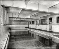 Washington, D.C., circa 1925. "Central High School swimming pool." National Photo Company Collection glass negative. View full size.
Looks FamiliarThe swimming pool at Catholic U. in D.C. was also in the basement of the gym (now the architecture department) and the proximity of overhead beams posed the same problems when using the diving board. You had to gauge your "lift" very carefully.
Grim SwimDepressing dip.
The horse pitMy granddaddy decided to build a pool for all the grandkids in the late '60s - took a backhoe and dug a really deep pit (15 feet) and formed up the sides with plywood and poured concrete - didn't smooth or sand it or anything. It cut our feet to shreds. He didn't make any steps or anything - just put an aluminum ladder in it. A couple months later a neighbor's horse fell in and drowned. Granddaddy took the backhoe and filled in the pool -- horse and all. Still the biggest horse tomb in East Texas.
Just Surreal!Goodness, what with the reflections and calm, clear water….. it's hard for me
to tell topsy from turvy. One thing for sure though: I don't like this place very much.
This is now the Cardozo poolLived pretty close to here.  Used the facility for bathing purposes (to many people at home)and got in a good swim to boot. Actually, learned to swim here.  Also to hold my breath for long periods under water.  I was an asthmatic, but not after Cardozo. 
Oh dearI'm going to assume the walls are a bright, cheery combination of pastel yellow and coral, the pool tiles are a lovely ocean blue, and the ceiling... well, we just won't look up.
Hey, the water is very clear. I do really love clear water. But I'm getting a touch of Inception-itis staring into this pool.
Central High School correctional institutionI didn't realize they had swimming facilities in PRISON.
Re: The Horse PitThank you for sharing that story-would make a hilarious scene in a movie!
Down the Drain at CardozoCentral High is now called Cardozo. I found this article about the closing of the pool, and there is a modern day photo of the pool at the end of the article, and you can greatly enlarge the "Tradition of Pride" photo. Um, still scary--but the mosaic numbers are still intact.
(The Gallery, D.C., Natl Photo, Swimming)