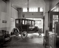 "Strobel Motor Co." New Model T in a Washington, D.C., Ford showroom circa 1924. National Photo Company Collection glass negative. View full size.
Lincoln?The name Lincoln appears in the front window, just ahead of the larger Ford script.  The dealership's name and address are unrelated to the name Lincoln and Lincoln cars have seldom been sold by Ford dealers.  Does anyone know the actual significance of the Lincoln name on this window? 
[The obvious answer might be that they sold Lincolns and Fords. Ford owned Lincoln; there were lots of Ford-Lincoln dealerships. Below are two more examples from the Washington area. - Dave]

High TechThe most modern piece of equipment in this picture is the metal file cabinet, which has not been improved upon since.
High tech?Actually, omitting anything to do with the car itself, the high-tech award should go either to the phone box on the baseboard on the left, or to the clock/timer thingy above the left corner of the window that sjmills pointed out. As to the latter, is it merely a clock, or a timing device? Rather poor design for a clock, as it's difficult to see if there are any hands. If a timer, is it for the lights as suggested, or maybe a burglar alarm? There appear to be thick black cables coming from the bottom of the case, and there's a round gizmo on the wall immediately below it, although that may be a light fixture.

Spare tireActually, that was the latest innovation in wheels at the time: they were called demountable rims. When you had a flat tire, you merely unbolted the rims and pulled it with the tire, replacing it with the one you carried behind the car, pretty much as we do today. Before that, it was expected from the user to know how to fix a punctured tube right on the spot. 
Of course the spare wheel and its corresponding innertube were extras, not included in the extraordinarily low price of the Model T.
No Stranger to FordsWashington Post Oct 9, 1921


Another Ford Agency
Strobel Motor Company Added to List of Dealers

To sell Fords at retail, E.T. Strobel has organized the Strobel Motor Company, and opened a sale and service station at 1425 Irving street northwest.
To the Ford automobile, Mr. Strobel is no stranger, having for twelve years been a superintendent of assembly for the factory, and the first to supervise the assembly of Ford cars in the Washington plant on Pennsylvania avenue.  After severing his connection with the company, he accepted a position with the R.L. Taylor Motor Company, Ford dealers, as superintendent, which position he occupied until engaging in business for himself.
In his new quarters he has ample room to render service on Ford cars, there being 17,000 square feet available.  The shop is equipped with all the latest time-saving machinery, including equipment for rebabbitting bearings and reboring cylinders.

Update: Mr. Strobel's business venture lasted for a few years but eventually dwindled. The October 9, 1927 Washington Post reports that the space at 1425 Irving street being used as the service department for I.C. Barber Motor Co.
Lost eraContrast this bare bones showroom with the slick extravaganza at todays Auto Mall. The earnest fellow with immaculately-oiled hair and a straw skimmer on his desk trying to sell you sisal floormats and a manifold heater might have been just as skeevy as todays Herb Tarlek Jr. pitching undercoating, but when he ducked into the back room he really was talking to the manager.
Spare?Not a tire, not a wheel, just a rim.... now that's some early work in changing tires!
AutomationIs that a timer to turn on the lighted signage?
Amazing tonal rangeEverything from under the wheel wells on the dark side, to what's outside the window. Those days (in one shot, anyway) are gone, I guess.
Mission StatementNote the mission (or "arts and crafts") style chairs.  This furniture was a bit out of fashion in the home by this date, though obviously still considered to be fine for this commercial setting.
In - T - resting!This showroom is a very far cry from today´s glass and aluminum dealerships! looks like the backstore of the neighbourhood's blacksmith; but it's really interesting to see how the Flivvers were displayed back in the day.
By the way, notice the little stains on the floor; I know that Model T's were "supposed" to leak some oil from time to time, but jeez, these were new cars! 
Nice photo as always.
Marking the TerritoryModel T's had no dipstick. To check the engine oil you leaned under the car and opened a petcock, if oil ran out you were good to go. No drip, you neeed to put some in.  
A few drips of oil back then was looked upon as better than the 24 pounds a day of manure from the horse the T replaced.
Lincoln Ford FordsonThe sign in the window also reads "Fordson". They sold Fordson tractors as well
(The Gallery, Cars, Trucks, Buses, D.C., Natl Photo)