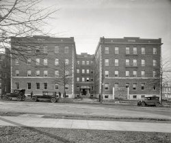 Washington, D.C., circa 1925. "Cedric apartments, 14th Street, W.H. West Co." Rents: $67.50 to $72.50 a month. National Photo glass negative. View full size.
4120 14th Street todayView Larger Map
AdequateNot the most exciting building ever, but, since it's still here, well suited to its purpose and well constructed as well!
Sturdy SidewalksIn the recently posted pictures of DC, the sidewalks are 3-squares across and appear, like this example, to be intact today.  Is this due to a more temperate climate than I am used to in Michigan or is it better engineering and workmanship?
Some With Porches?"Some with shelves," they should say, if the real porches aren't around back.
Rise and fall of view camerasConvergence of parallel lines is common in building photos today. The use of a view camera, with its adjustable front and back planes is almost a lost art. How many people today know what rise &amp; fall, swing, tilt, and shift controls are?  Specifically, rise of the front lens plane in a view camera makes architectural photos powerful. Compare this Cedric photo to the ugly distortion you will see on Google Street View.
Hope they had Concierge service!$72.50 a month in 1925? That was a small fortune for people who were making maybe a dollar or two a day.  I remember we lived in a small three bedroom flat in the fifties and my parents paid $30 a month in rent.  My mom talked about when she and my dad married in the early thirties and lived in a fancy furnished apartment in a tony part of town that went for $16 a month. And that was a lot of money during the Depression.
Tapestry Brick Apartments

Washington Post, Feb 7, 1926 


New Apartments in Northwest

New four-story, tapestry brick apartment structure at Fourteenth and Upshur streets northwest, which is just receiving its finishing touches.  The building was designed by W.R. Lamar and contains 40 housekeeping apartments of three and four rooms, some with porches.  W.H. West Co. are the exclusive agents.


TreesInteresting to compare the original photo with the Google Street View.  The tree in the middle doesn't seem to have survived (there is a small tree in its place in the present day), although the two on either end of the building appear to be flourishing.
Judging by the for-sale signs posted out front, it looks like the building has gone condo (and I would wager to say that condos in a prewar building in NW DC go for a pretty penny these days).
I used Street View to go around the corner and look down the back of the building, and it does appear that there are structures that come closer to approaching actual porches than what's on the front, although they're still pretty tiny.
Petworth / Columbia Heights1BR condos in the building are going for $90k to $200k.
http://www.trulia.com/property/1081317735-4120-14th-St-Nw-45-Washington-...
Not as pricey as I thought"What cost $67.50 in 1925 would cost $822.46 in 2008." according to the Inflation Calculator.
Hudson Super SixThe car second from the left is a 1925 Hudson Super Six Coach, which was the company's most popular body style.  This particular car is of the second series with a new modified body introduced in March of that year, and sold for $1,250.  Due to increasing sales volume, by October the price had been reduced to $1,165. Hudson was the world's largest builder of six cylinder cars, and the #3 automaker in the U.S. in 1925.  Thanks Shorpy!  You continue to be the best place on the web to see original vintage photos of Hudson automobiles!
Grapes of WrathAs Steinbeck readers will recall, Al Joad picked a 1926 Hudson Super Six from the jalopy lot to make into a truck to haul the family to the Promised Land, because it was a popular model and the junkyards would have plenty of spare parts. 
(The Gallery, Cars, Trucks, Buses, D.C., Natl Photo)