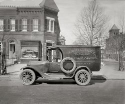 Washington, Sixth and L streets S.W., circa 1926. "Semmes Motor Co. J.W. Hurley truck." National Photo Co. Collection glass negative. View full size.
Long GoneView Larger Map
From the look of things everything in this photograph was torn down long ago.  Even the intersection itself was obliterated.
Ohhhh...So the rim clamps onto the spoked part of the wheel? Gotcha.
I learn something new everyday around here. Thanks Dave!
Dings and dentsLooks like this truck had a few scrapes with some eager kiddies! I always wondered about those spare tires without rims. How where you supposed to change that along the roadside? Wouldn't you need a tire machine, and air pump? Was the extra tire just for use when you were towed to the garage?
[This spare is already on a rim. - Dave]
Fortified TreesI'm surprised the trees are gone, they appear to be well protected in their fortifications. Also I remember the iron fencing from my childhood in Philadelphia.  We used to jump over the fences in the alley, occasionally our pants would get caught on the post and rip. It didn't hurt as much as explaining to our mothers how our pants ripped.
One more question for Dave, is the lady or brand advertised on the poster in the window identified? [Afraid not. - Dave]
Thank you for another glimpse into American Life.
Aaah! The Candy man!When we were kids my grandfather owned a small grocery store. He sold mostly  penny candies from a large glass display in front. If you had a nickel, it might take 10 minutes to decided exactly how to spend it all. There was a candy man named Ralph. He would show up every two weeks with a station wagon full of candy to restock the display. My sister and I and our five cousins knew when Ralph was due to return. I remember dancing around yelling "The candy man's here!" when Ralph's station  wagon pulled up to the store. Ralph would have us kids try all his new candies. We became his trusted panel of candy judges. Grandpa usually bought his candy based on our opinions. I'll bet this candy man had similar candy judges on his route.
(The Gallery, Cars, Trucks, Buses, D.C., Natl Photo, Stores & Markets)