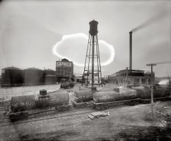 A glimpse at the industrial side of Washington circa 1925, labeled "Capitol Refining Co. plant." This tank farm, where the Pentagon stands today, was described at the time as being in "Relee, Alexandria County, just south of the highway bridge." National Photo Co. Collection glass negative. View full size.
OMG!I hate it when Giant Amoebas attack!
Cattle, Cotton &amp; Oil, Oh My!I find it curious how this site evolved from a stockyard and abattoir (slaughterhouse) into a cottonseed oil refinery and then finally the petroleum refinery pictured. The cotton-seed oil may have been used for food or industrial applications such as lubricants and paint.  I wonder if equipment for refining cottonseeds could be reused to refine petroleum?
[Were any of these petroleum tanks? - Dave]
Update: After seeing the later  White Dome post, I am pondering if perhaps the "refining" refers only to vegetable and animal oils and not to petroleum products at all.  I guess its my fossil-fuel-centric lifestyle that led me to the conclusion that this was a petroleum refinery - that and pre-conditioning due to the long series of photos of service stations on Shorpy.

Washington Post, Jun 5, 1908

Packing Plant For City
Washington's industries are to be increased here of a plant with an annual output valued at from $4,000,000 to $5,000,000.  The company, to be known as the Columbia Cotton Oil and Provisions Corporation, proposes to absorb the Washington and Virginia Stock Yard and Abattoir Company and to enlarge the plant and add equipment, not only for slaughtering of cattle, but for the refining of crude cottonseed oil.
...
The proposed plant, it is said, will be the only one of its kind east of Chicago and south of New York, and the only complete compound plant on the coast between New York and Savannah.
...
The annual capacity, according to figures submitted to the manufactures committee of the Chamber of Commerce, will be 100,000 barrels of crude cotton-seed oil, 125,000 hogs, 10,000 cattle, and 25,000 sheep and calves which will be converted into lard, lard compound, lard substitute, cooking oils, lard stearine, oleo stearine, hams, bacon, sausage, canned meats, fertilizer, hides, and a variety of fresh cuts to be put on the market.

Washington Post, Jun 2, 1913

Refiners Buy Oil Plant
The Capitol Refining Company, which was recently granted a charter by the Virginia corporation commission, has purchased the plant of the Columbia Cotton Oil and Provisions Corporation, at Relee, near Arlington Junction, Alexandria county.  The Capitol Refining Company is a subsidiary of the Jacob Dold Packing Company, an independent concern, whose main establishment is in Buffalo, N.Y., and its announced that about September 1, after extensive repairs to the plant, operations will be resumed.

Relee, Va.Is it possible that Relee stands for Robert E. Lee? His estate was nearby.
[You are correct. The use of Relee, Virginia, as a place name seems to have begun in 1909, with the establishment there of a post office, rail stop and telegraph office, all connected with the Columbia slaughterhouse and rendering plant in what used to be Alexandria County, at the current location of the Pentagon. By 1935, use of the name seems to have pretty much stopped. - Dave]
Washington Post, November 11, 1909

Finishing Big Plant
$450,000 Abattoir and Refinery Soon to Operate.
To Employ 200 Persons. Industry at Arlington Junction Will Help Virginians.
Within ten days the Columbia Cotton Oil and Provision Company will begin operation of its $450,000 plant, which has been building near Arlington Junction across the river for the last nine months, and will mark one of the greatest strides forward in the industrial development of Washington.
In the abattoir 4,000 hogs a week will be killed, and a strong demand will at once be created in Virginia and surrounding States for porkers. ... The cotton oil refinery and abattoir will be run in conjunction in the production of lard compound, which will be one of the most important outputs of the establishment.
... The plant essays the importance of a town which has been recognized already by the establishment of a railroad stop and a postoffice by the United States government. The name is Relee, in honor of R.E. Lee. It is Relee postoffice, Relee station, and Relee telegraph office, all of which are in operation.
Day of JudgmentCould the "accidental" location of the "cloud" be any better placed in terms of composition? Actually makes the shot better, I think.
(The Gallery, D.C., Natl Photo, Railroads)